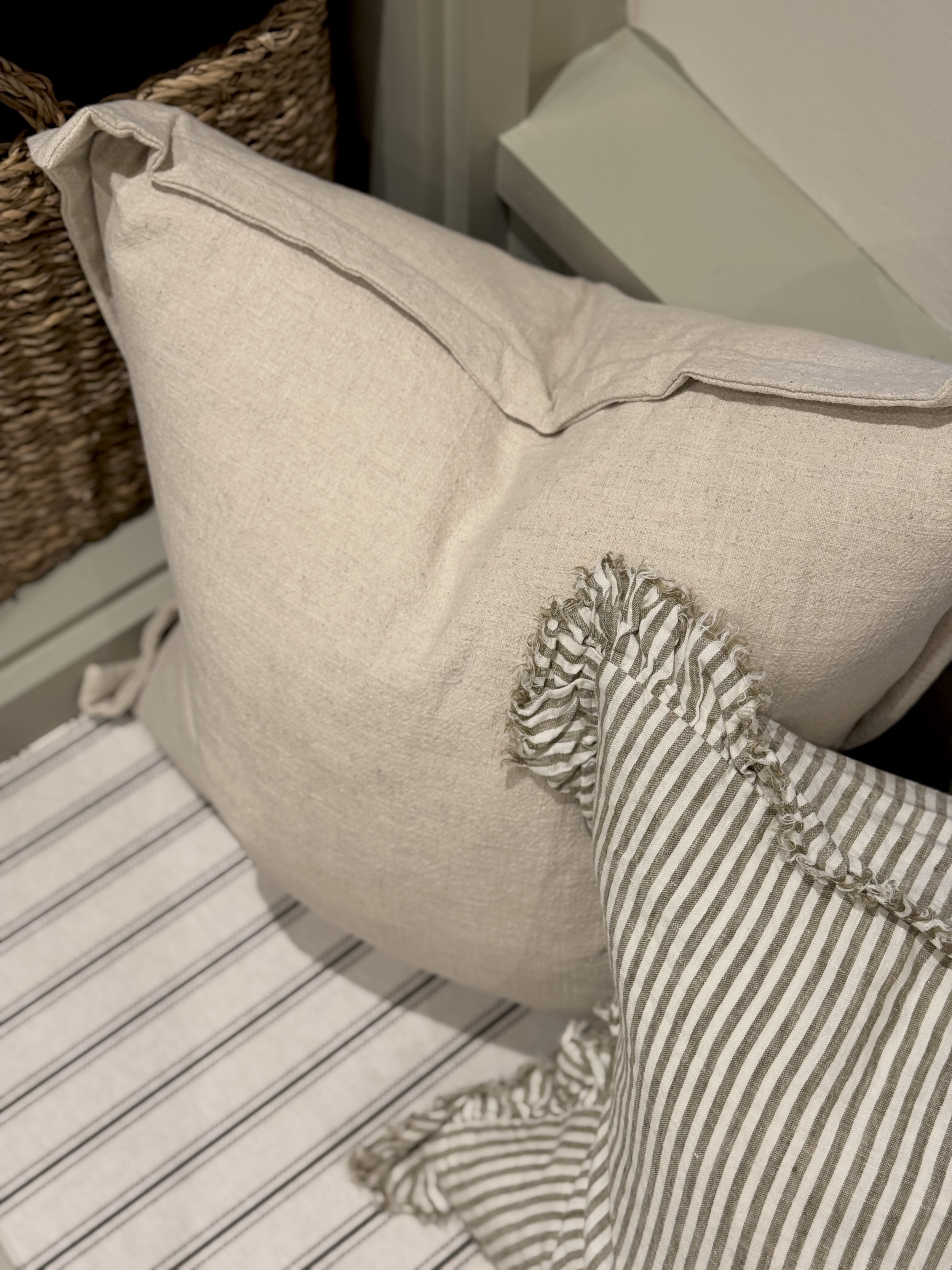 Layered linen cushions and striped patterns add warmth and softness to the bespoke window seat, enhancing the home's relaxed, timeless aesthetic.