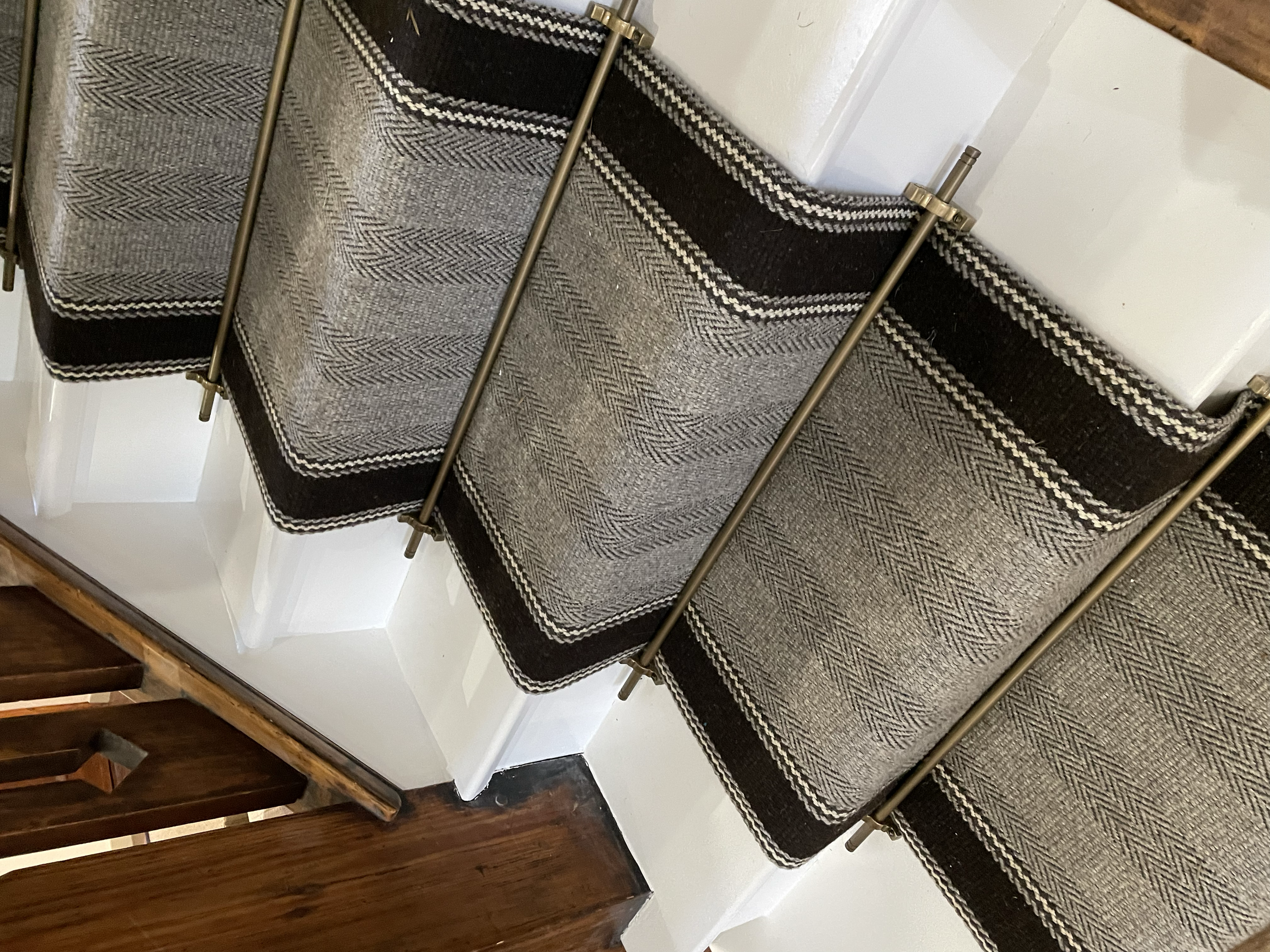 Close-up of a bespoke wool stair runner with antique brass stair rods in a Grade II listed family home.