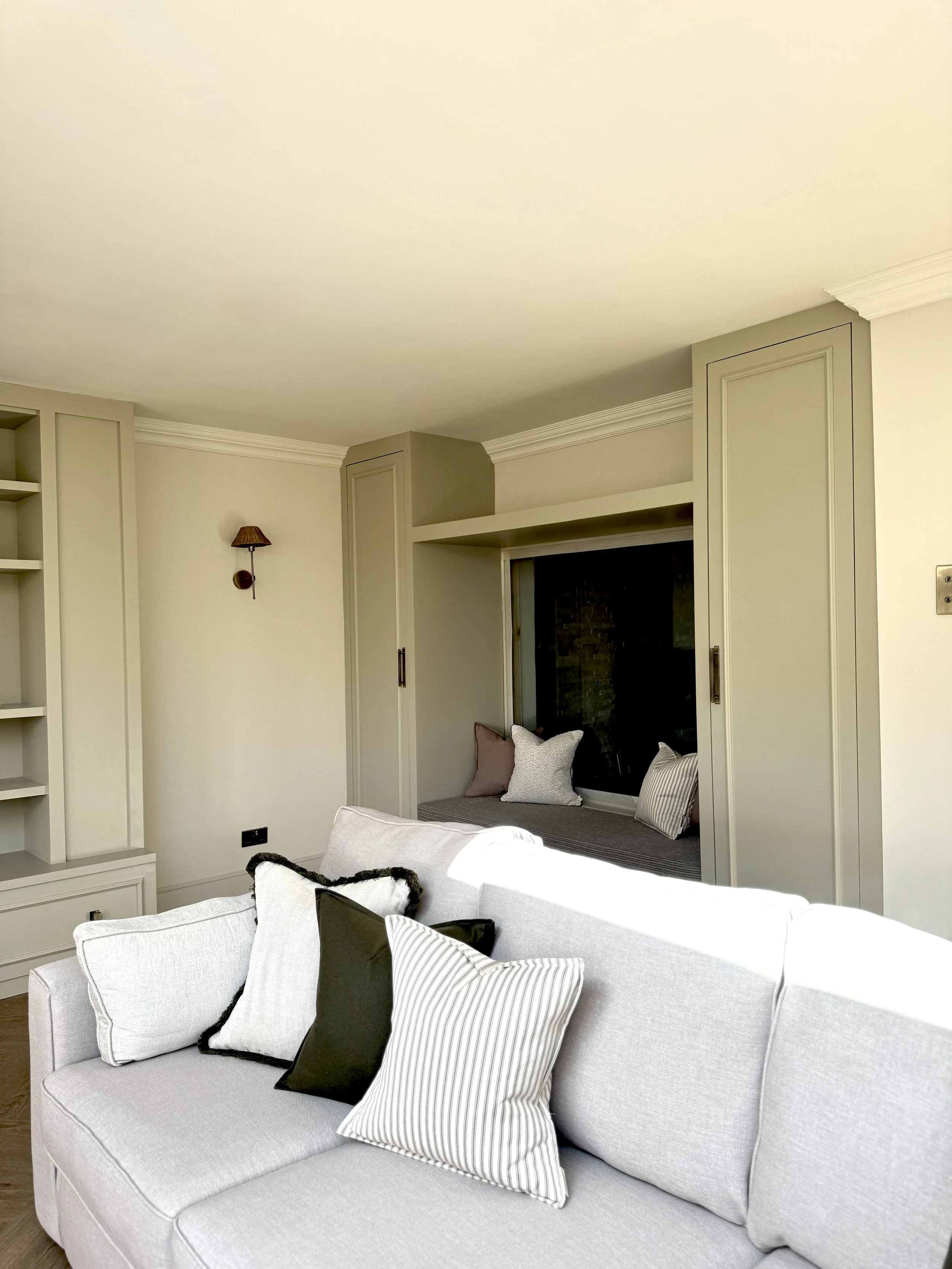 Bespoke living room cabinetry frames an integrated window seat and media wall, combining elegant storage with carefully considered architectural detailing.