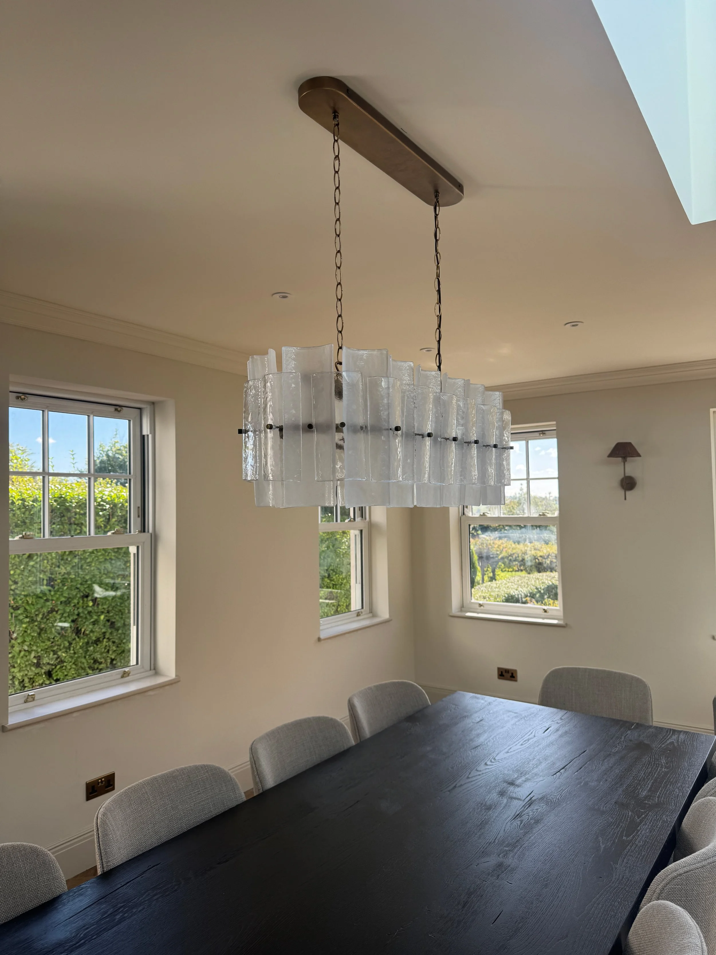 Sculptural textured glass pendant lighting creates a striking focal point above the dining table while complementing the home's timeless interior palette.