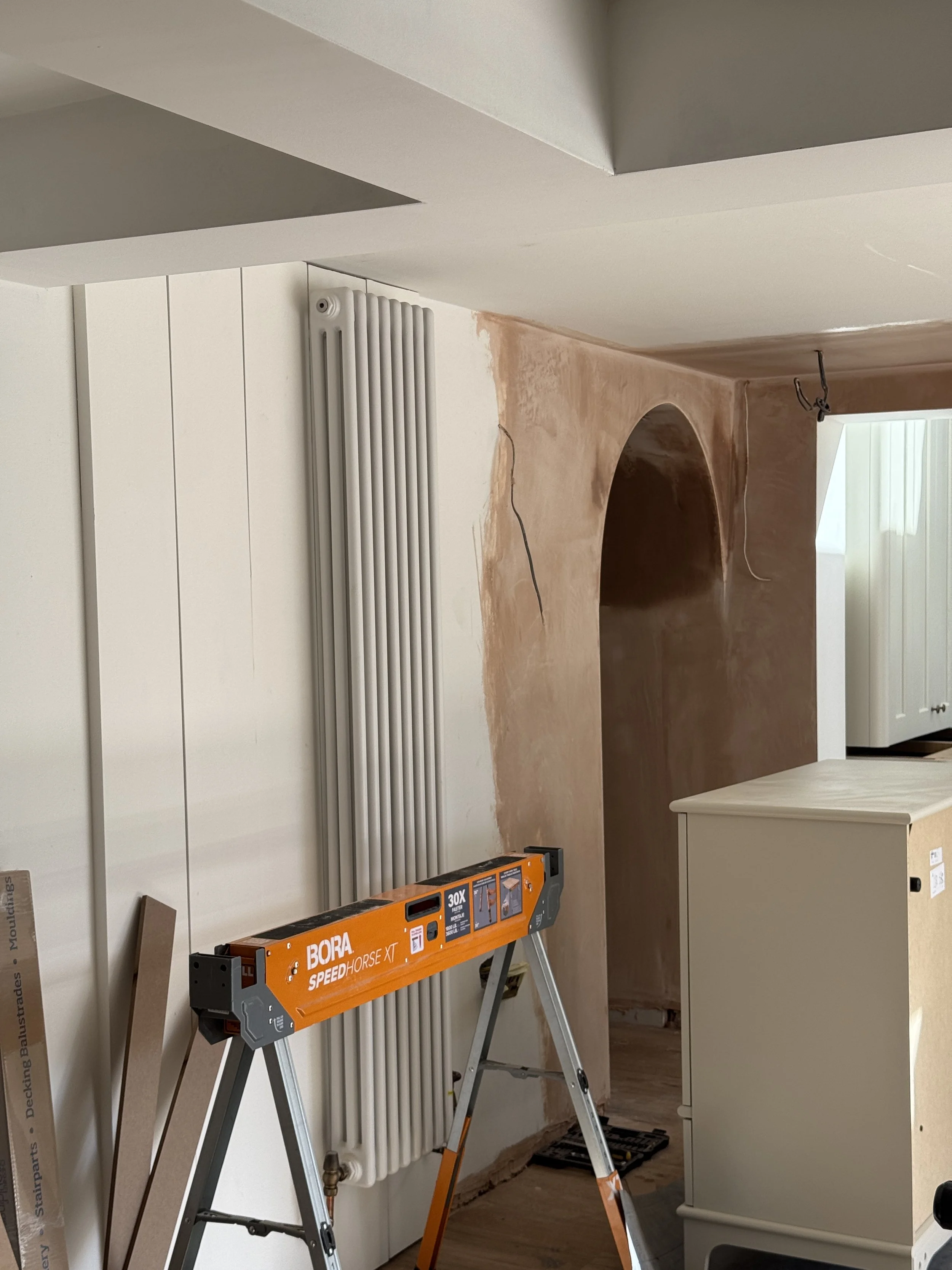 Soft plaster archway introducing gentle architectural curves and connecting the kitchen with adjoining living spaces.