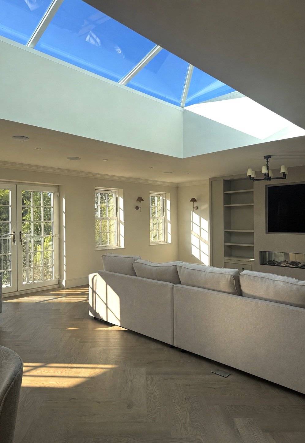 The open-plan living space connects the kitchen, dining and lounge, with large roof glazing flooding the home with natural light throughout the day.