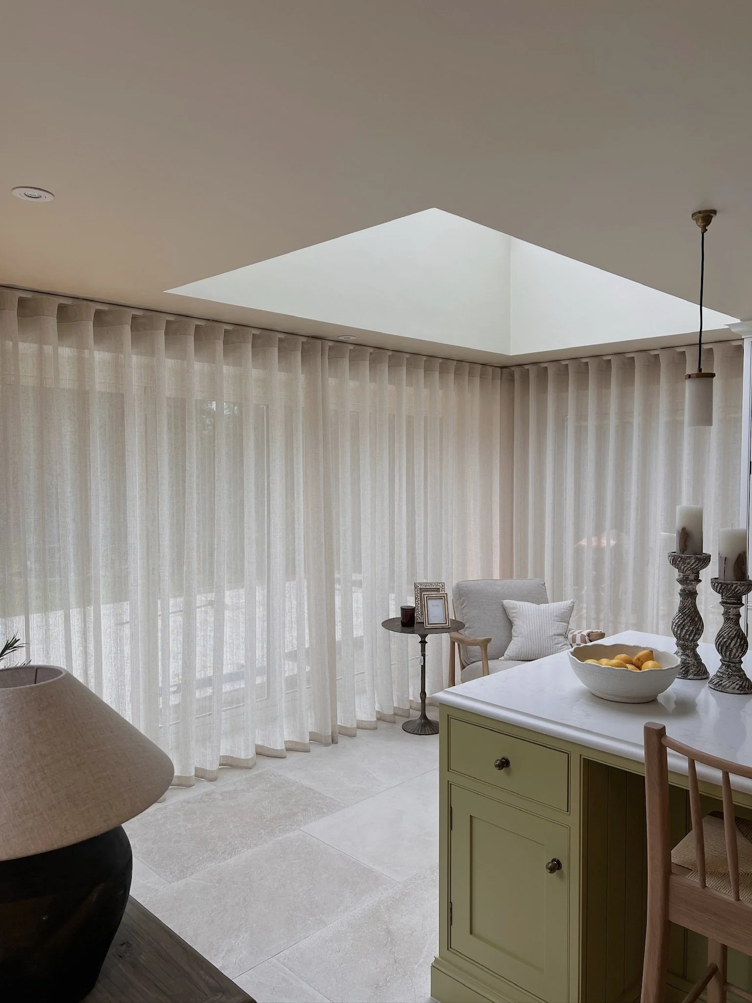 Soft linen sheer curtains and large roof lantern flooding the open-plan kitchen with natural light.