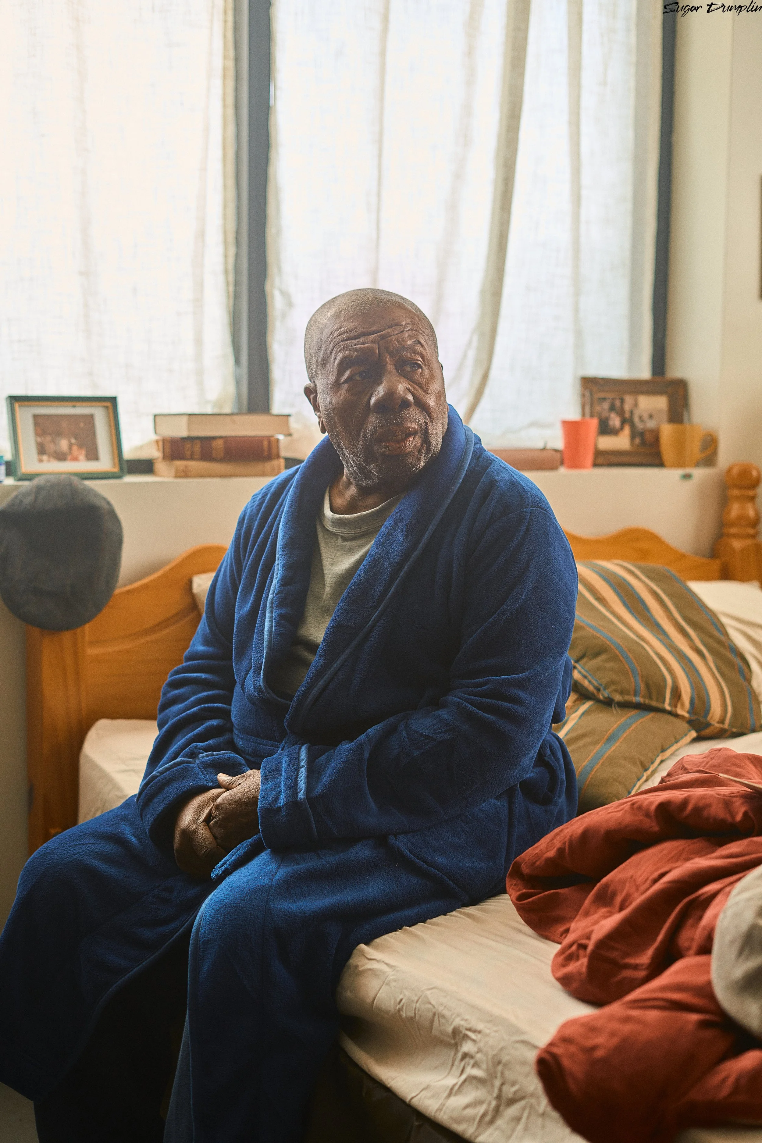 Oliver Samuels sitting on the bed, preparing to play Desmond James in the short film Sugar Dumplin directed by Tristan Barrocks. Written by Tristan Barrocks. Produced by Natanya Barrocks.  