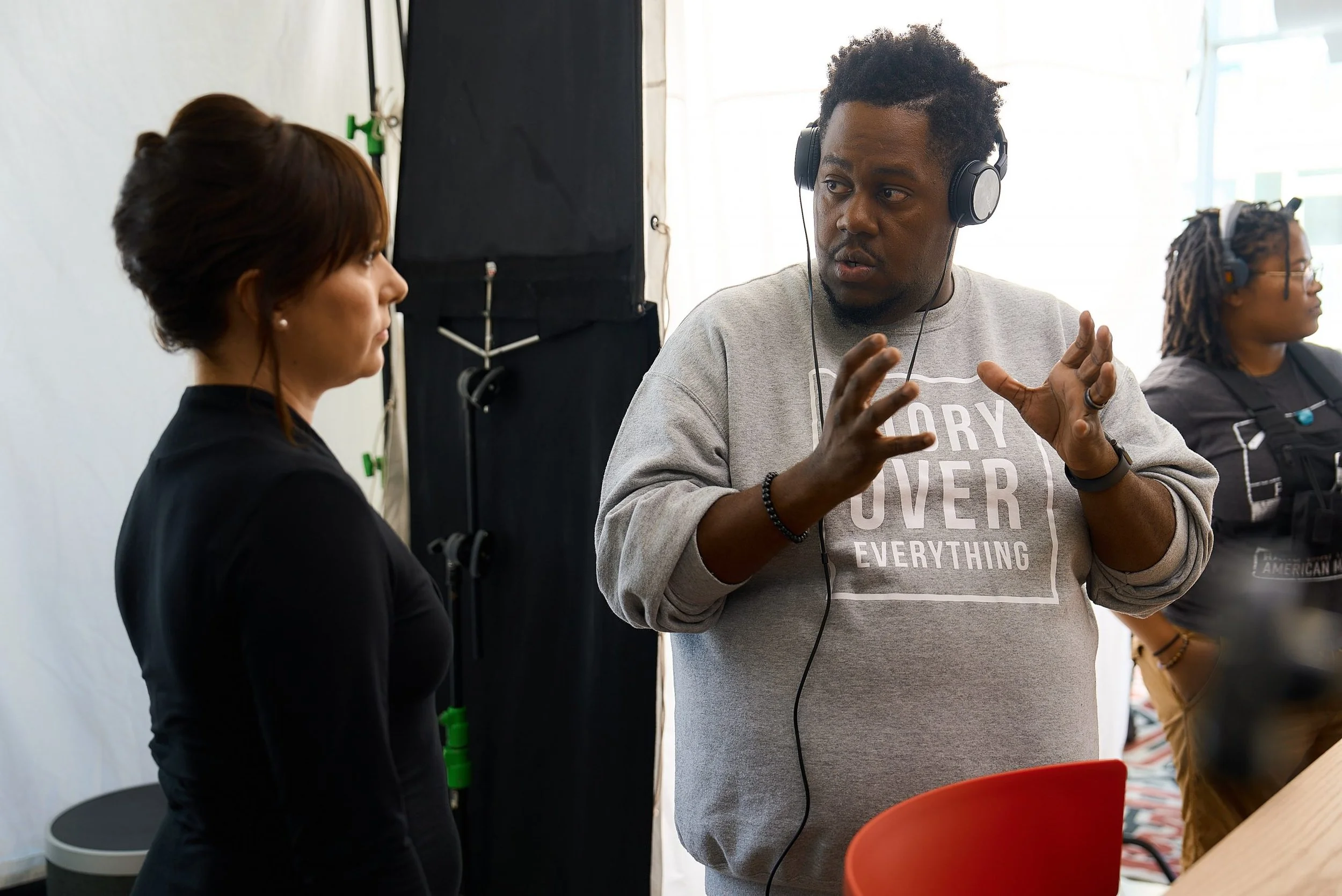 Tristan Barrocks directing on the set of the film Wallflower back in 2022. Passionately sharing his perspective on the scene, wearing a Glory Over Everything sweater, great with a woman looking onward
