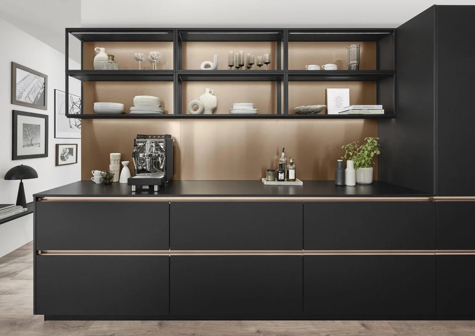 Modern kitchen with black cabinetry, open shelves, a coffee machine, bottles, and decorative items on the countertop and shelves.