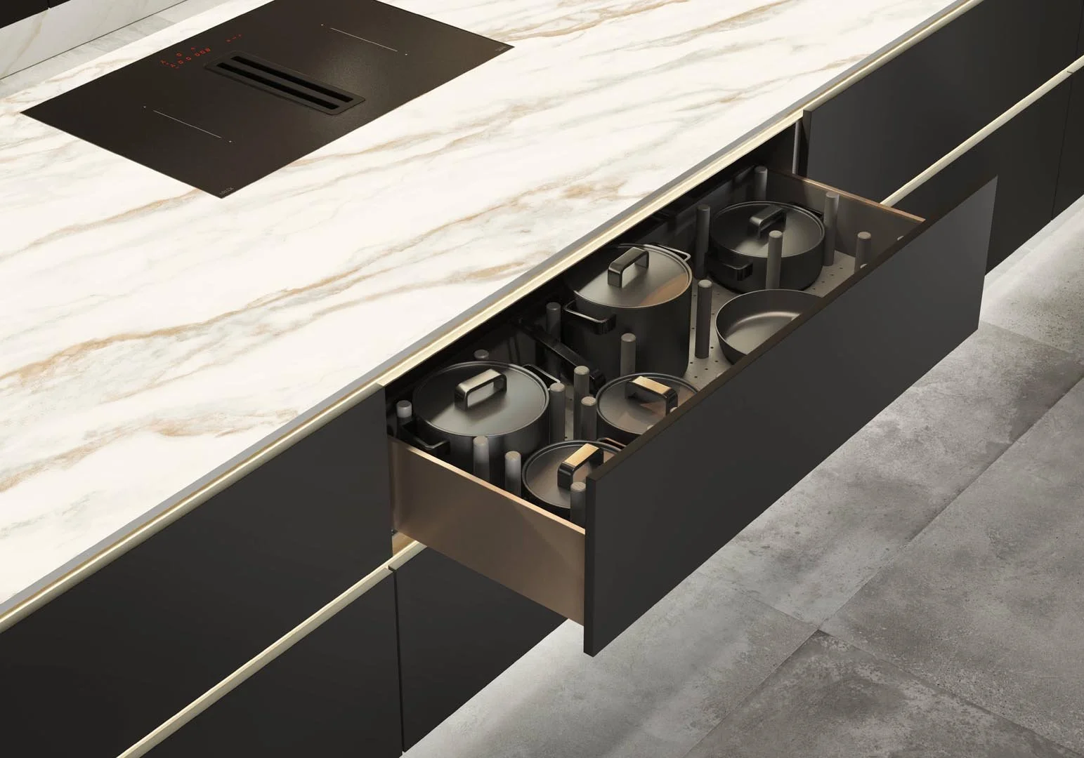 Open kitchen drawer with black pots and pans with handles inside, beneath a marble countertop with a black stovetop.