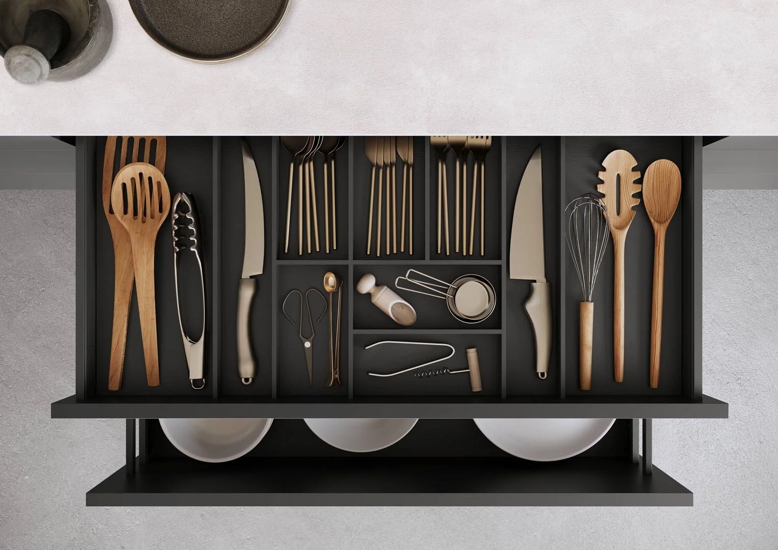 Kitchen drawer with various utensils including wooden spatulas, metal tongs, knives, a whisk, a garlic press, and small measuring spoons, organized in compartments.