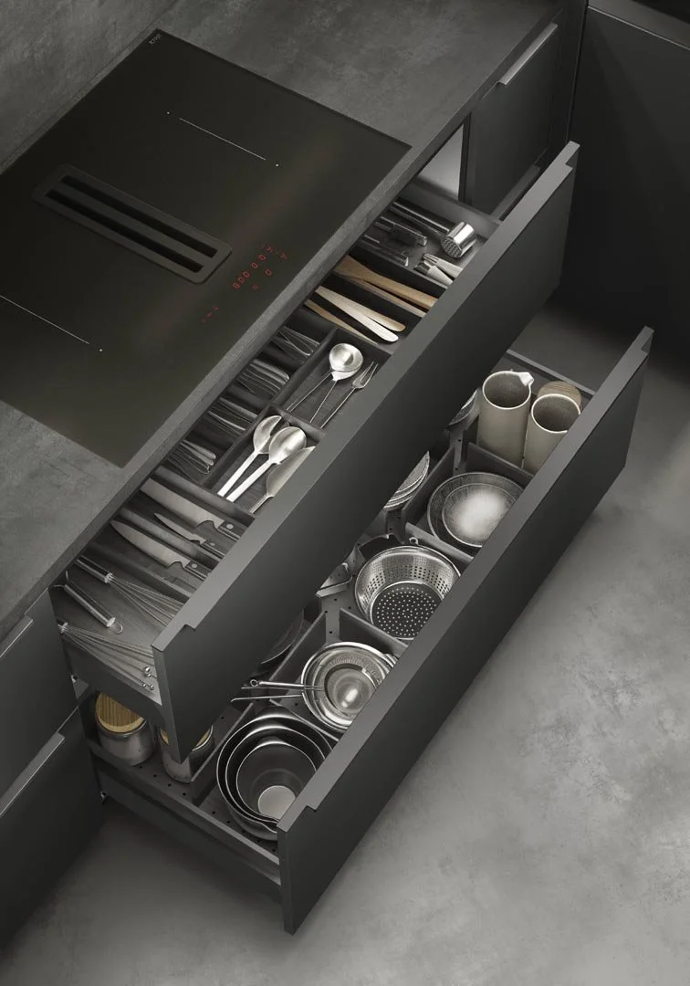 Open kitchen drawers filled with utensils, knives, bowls, strainers, and other kitchen tools.