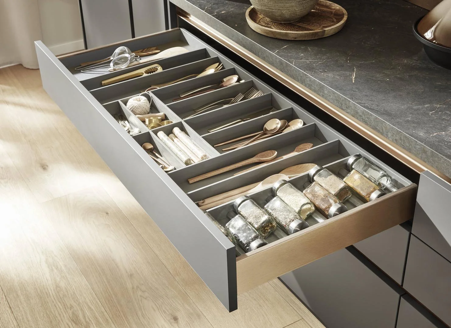 Open kitchen drawer containing neatly arranged utensils, spices, and kitchen tools.