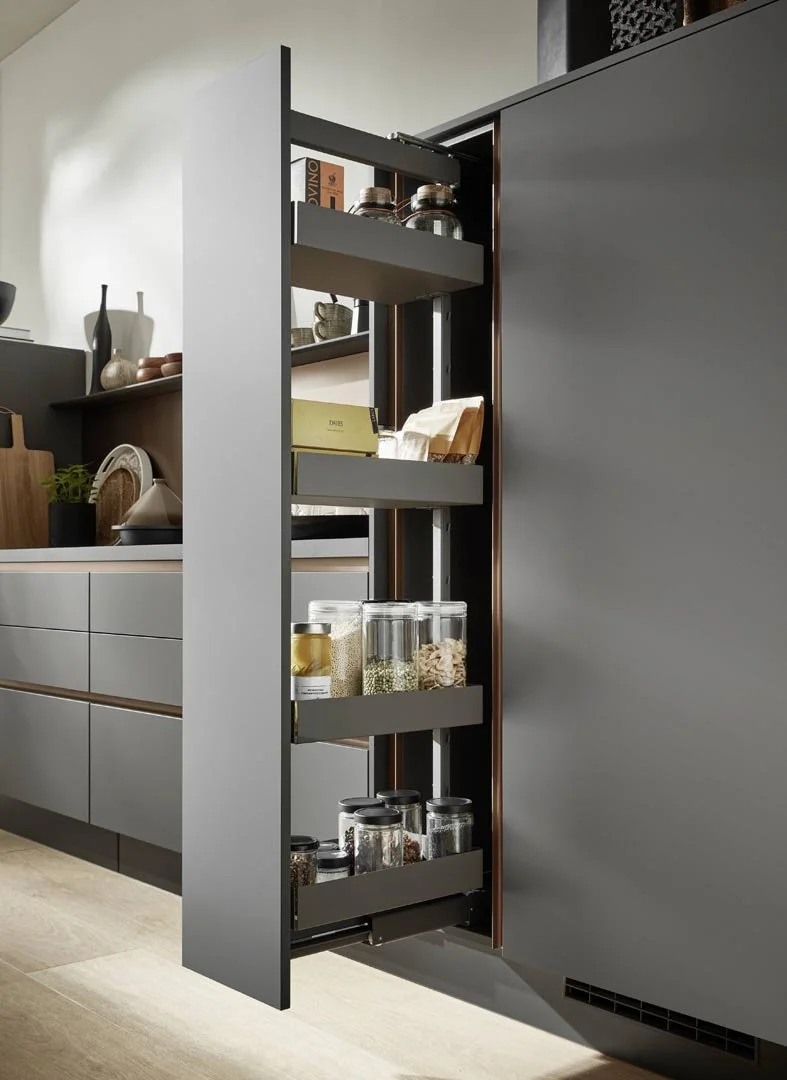 A kitchen cabinet with pull-out shelves filled with jars, containers, and pantry items.