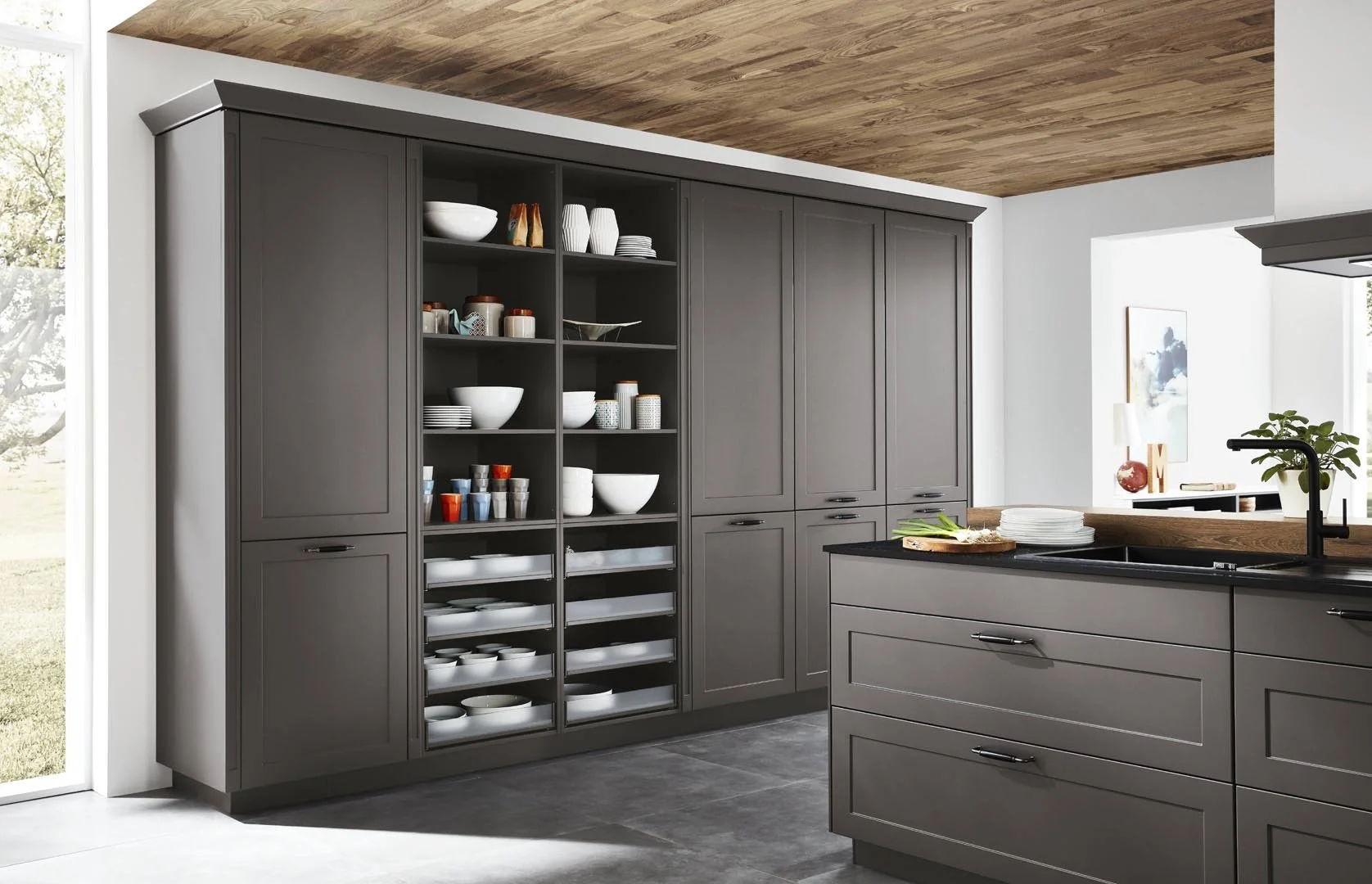 Modern kitchen with gray cabinetry, open shelves displaying dishes and bowls, black countertops, and a wooden ceiling.