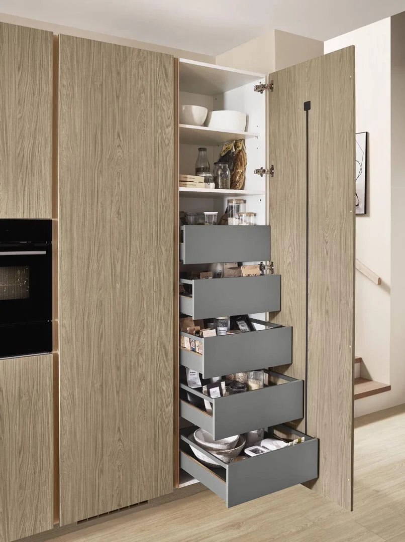 Open kitchen cabinet with multiple shelves and gray pull-out drawers containing various kitchen items and pantry supplies.