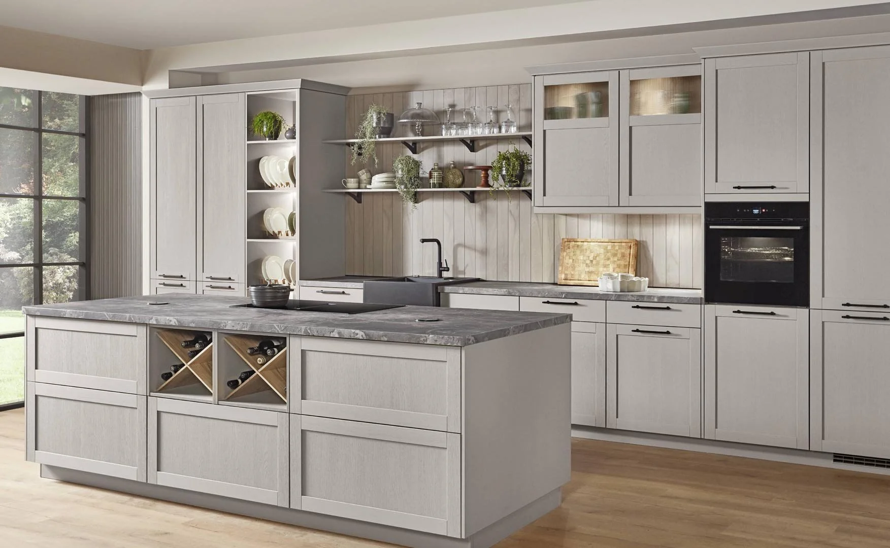 Modern kitchen with light gray cabinetry, a marble island, open shelving with dishes and glassware, and a large window with trees outside.