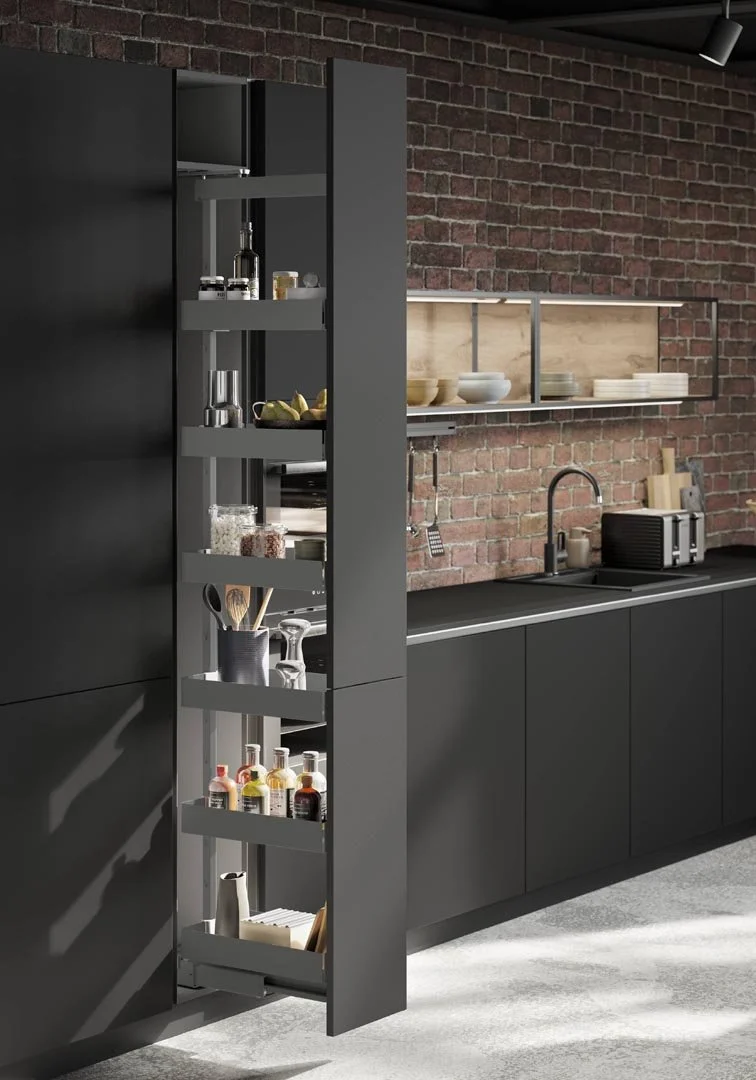 Modern kitchen with black cabinets and a brick wall, featuring open shelving with plates and bowls, and a pull-out pantry with spices, jars, and cooking utensils.