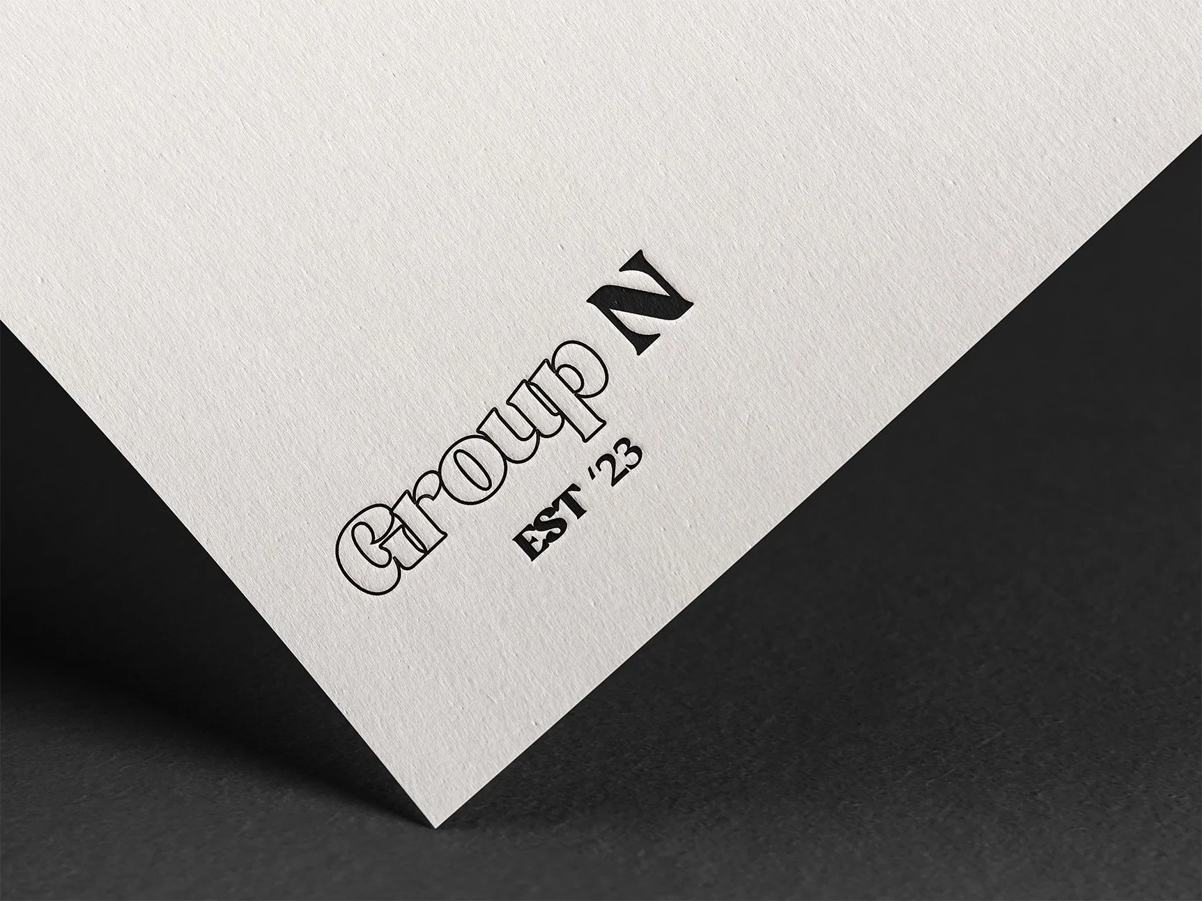 Close-up of a white textured paper with black text that reads 'Groupon,' 'EST '23,' and a partial view of a black background.