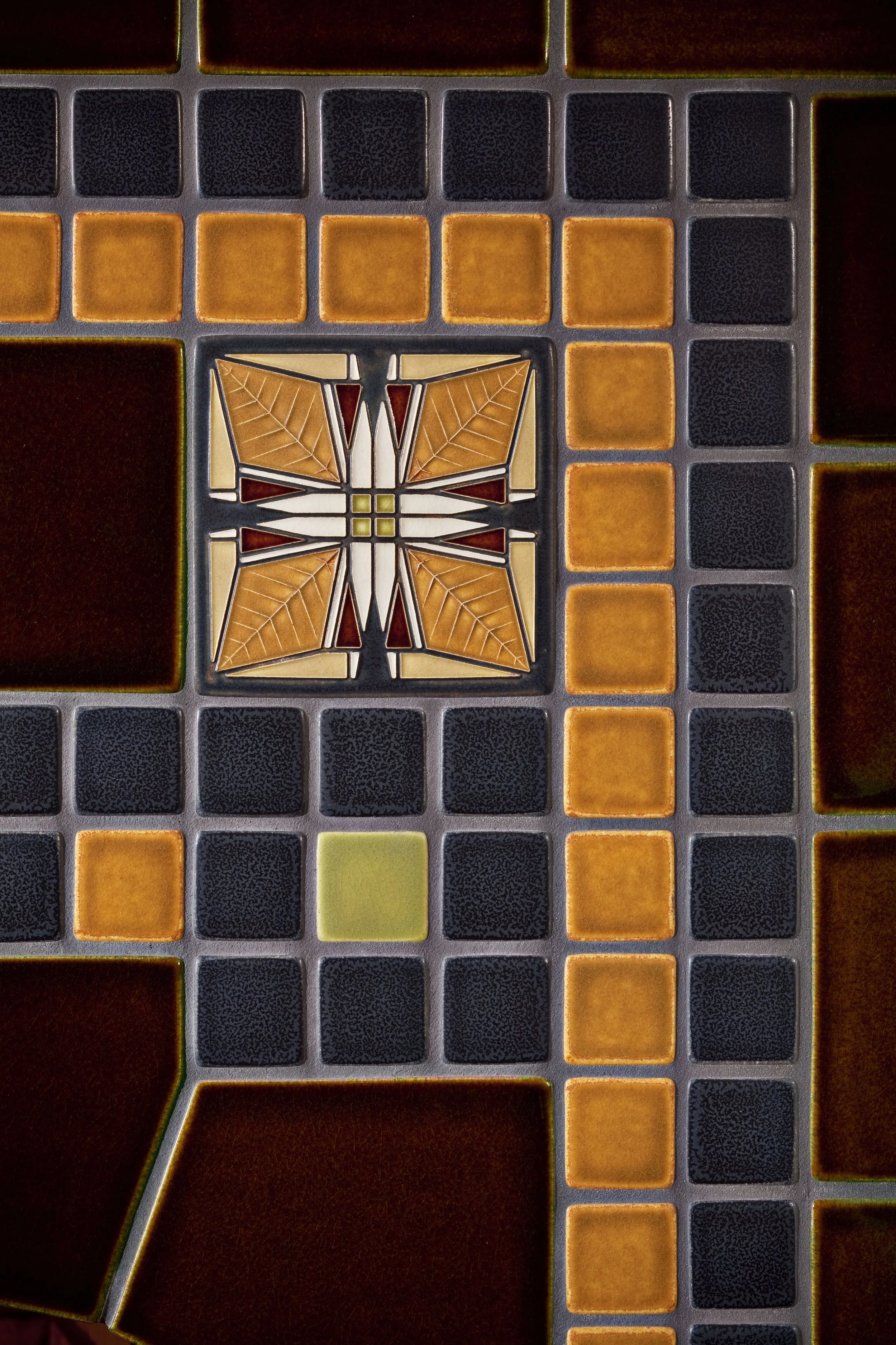 Patterned tile floor with a butterfly design in the center, surrounded by geometric square tiles in red, orange, black, and yellow.