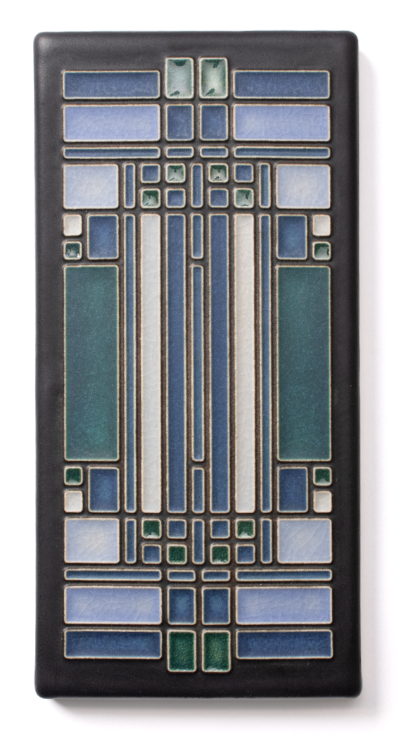 Colorful vintage ceramic tile with geometric patterns in blue, green, and white on a black rectangular background.