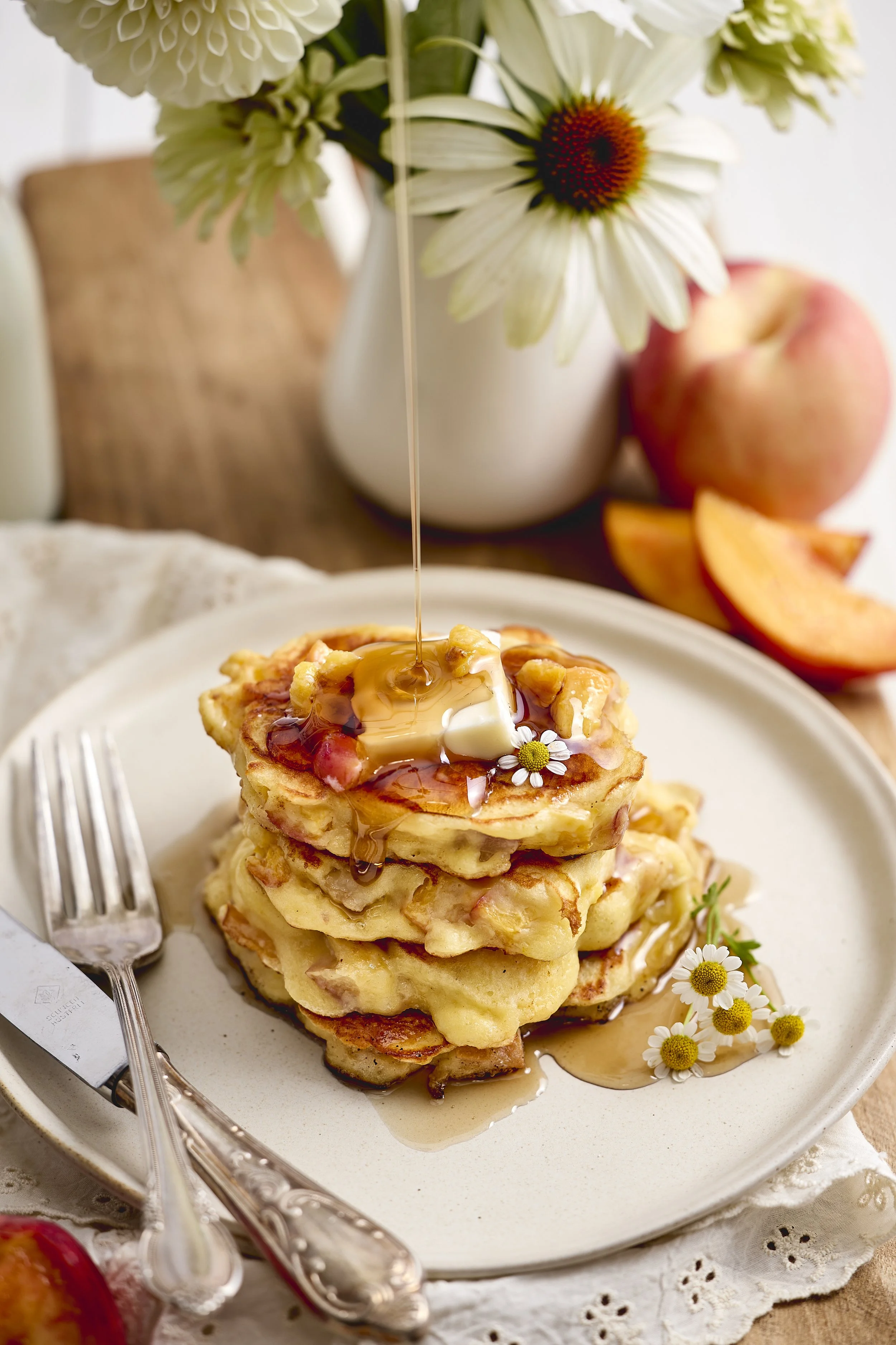 recipe photography featuring stack of high protein peach pancakes with maple syrup
