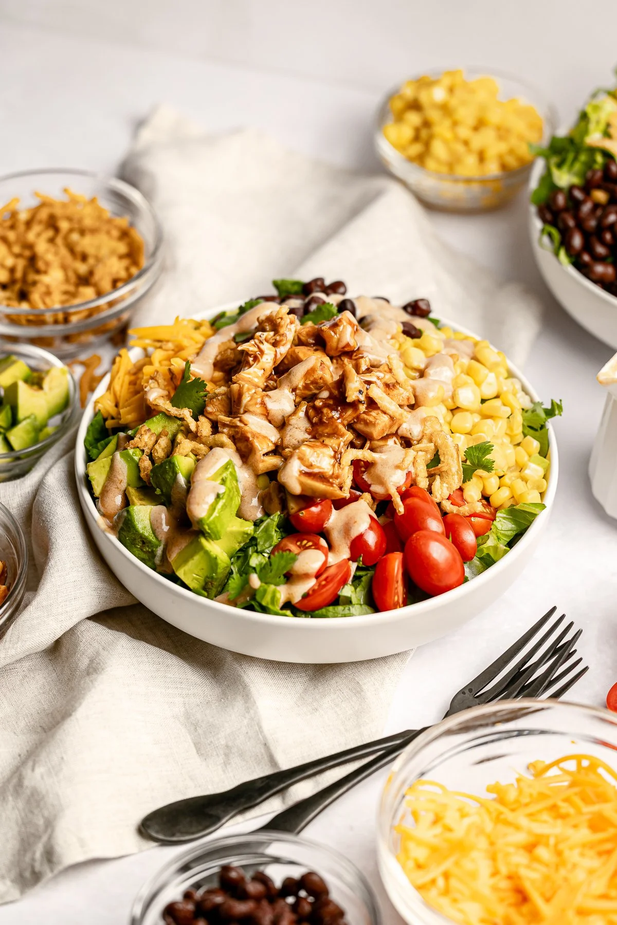 Vibrant bbq chicken bowl with romaine lettuce, cilantro, black beans, corn, tomatoes, avocado, and juicy grilled chicken, drizzled with a creamy bbq ranch dressing topped with crispy French onions. A colorful, flavorful, and high protein meal.