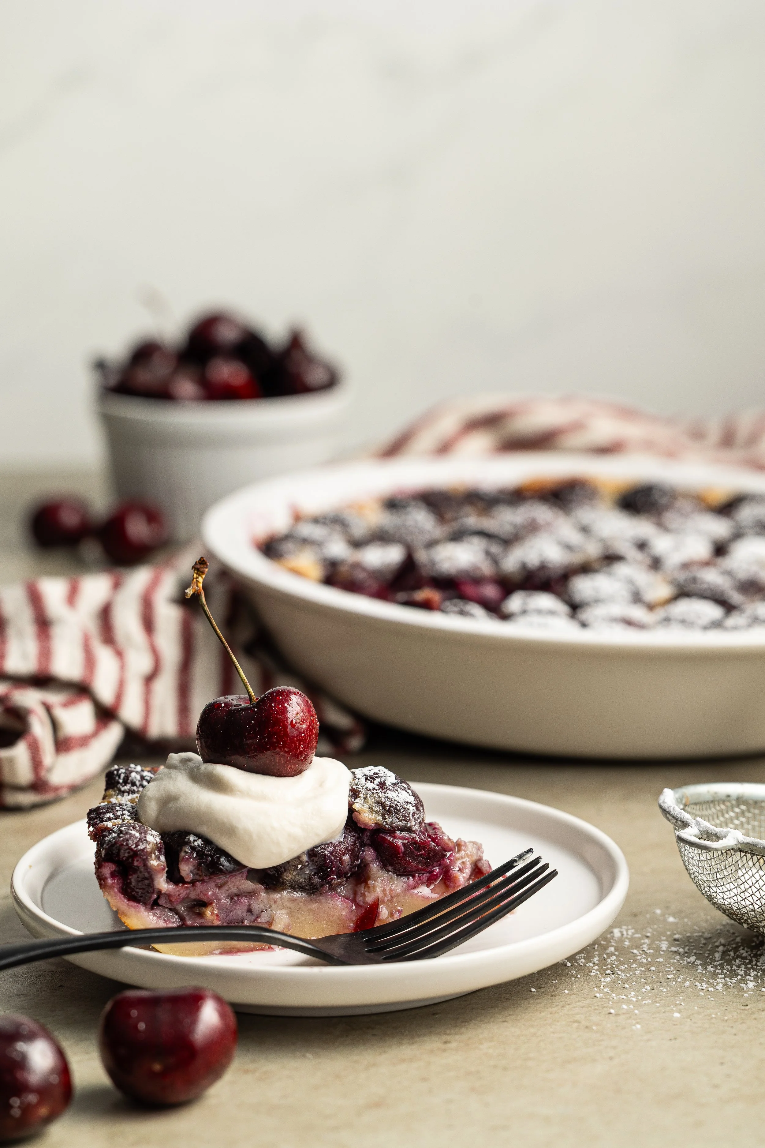 Cherry claflouis topped with whipped cream and a dark sweet cherry