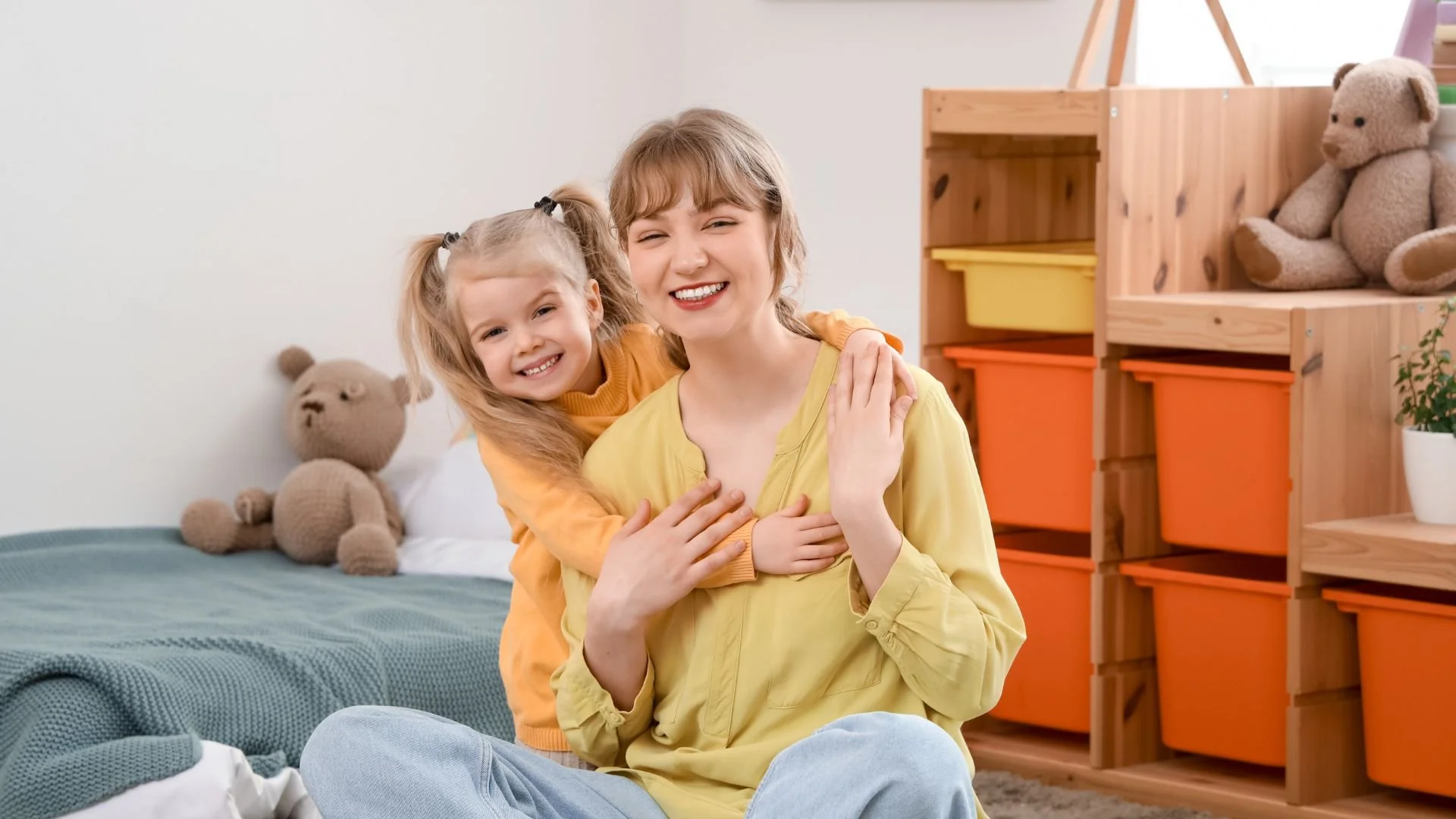 Smiling professional summer nanny hugging a young girl in a clean playroom, trusted private childcare solutions by A Mother's Prayer Placement.