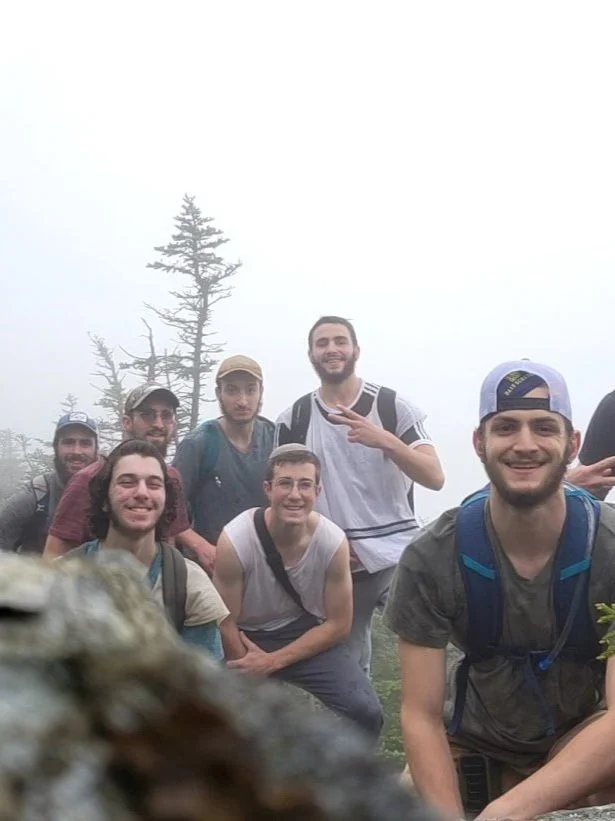 Group of men posing together outdoors in nature.