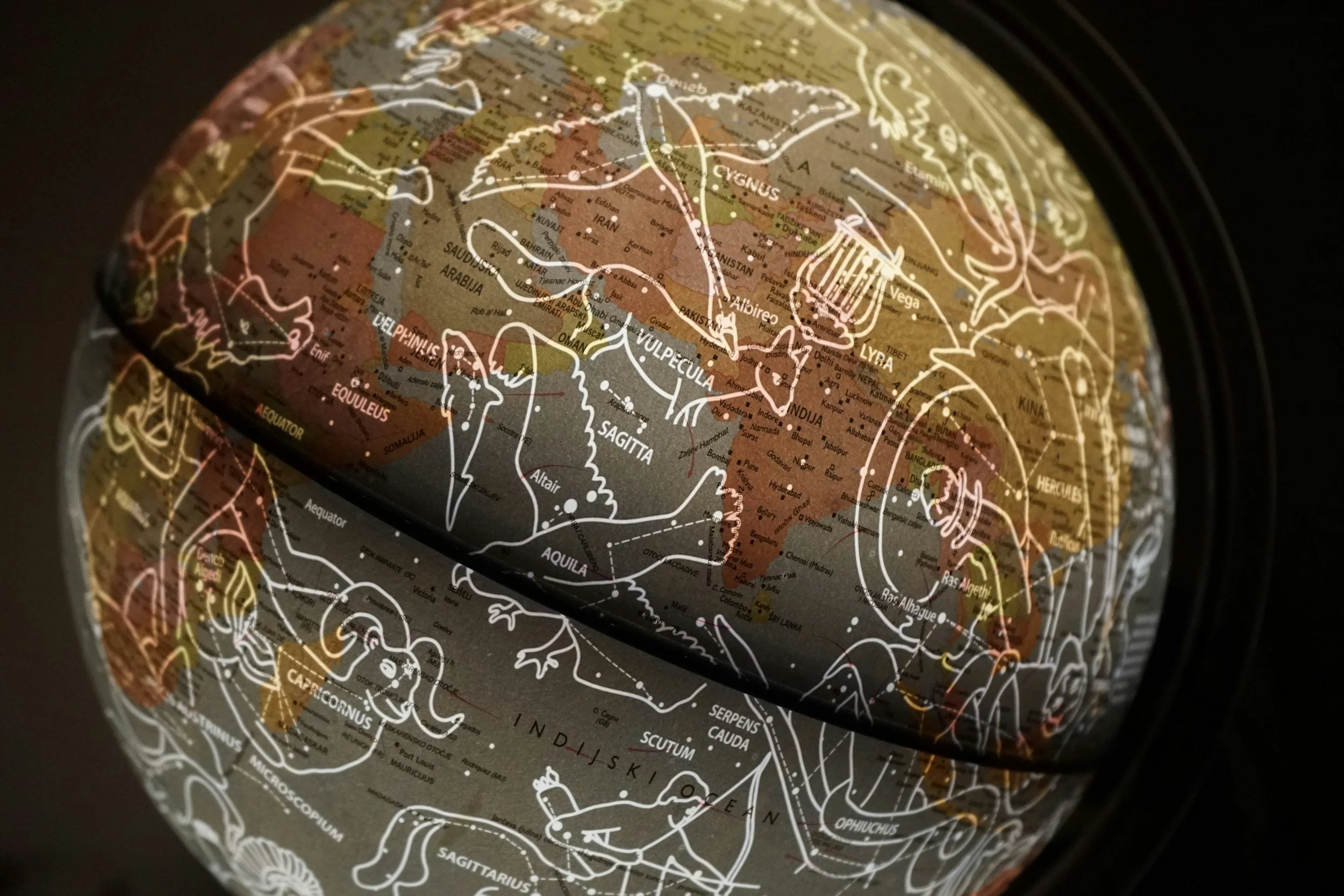 Close-up of a globe with constellation outlines overlaying a map of Asia, Africa, and Europe, showing some countries and geographical features.