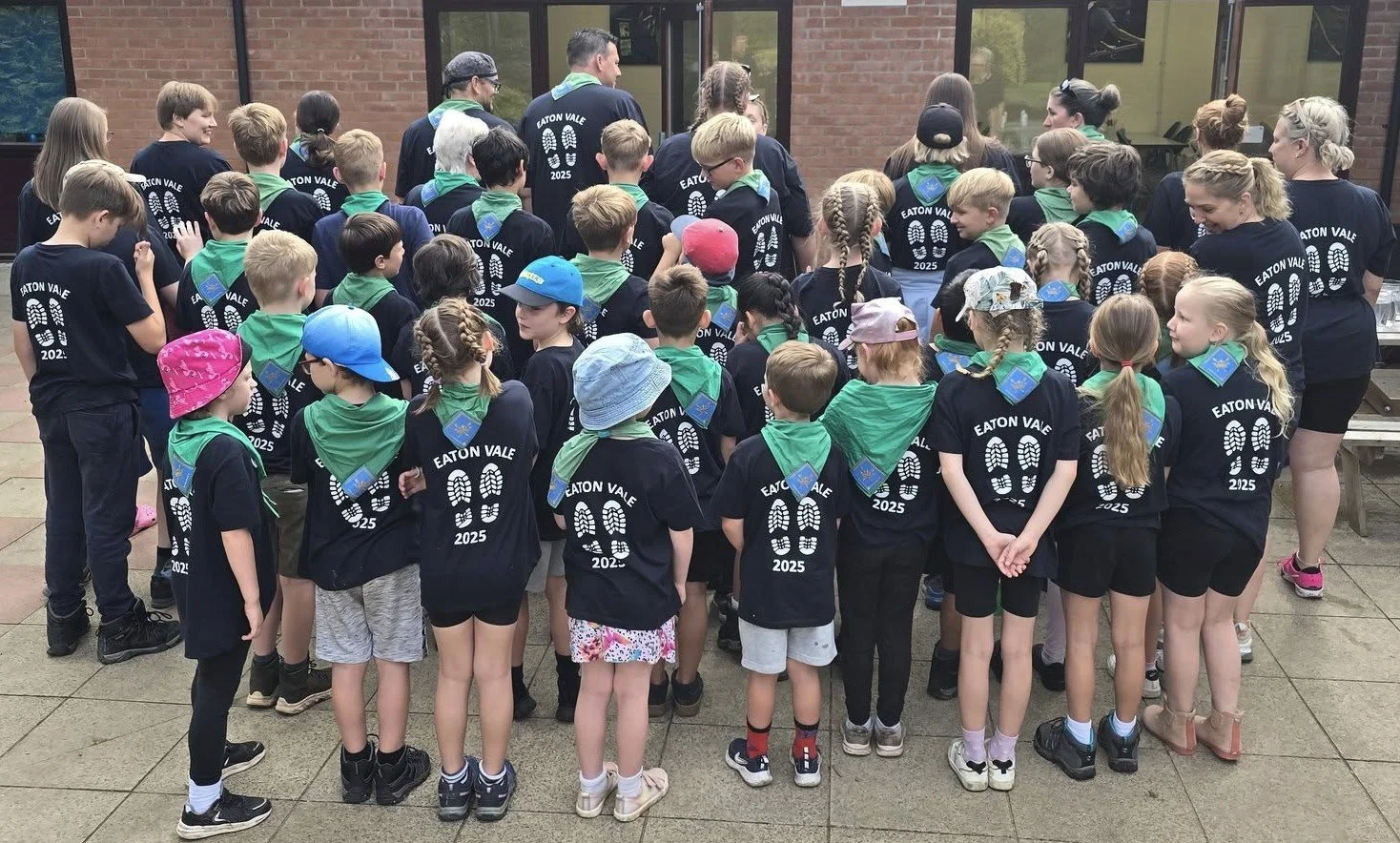 Beavers, Cubs, Scouts and leaders stand with their backs to the camera showing off their matching Eaton Vale t-shirts.