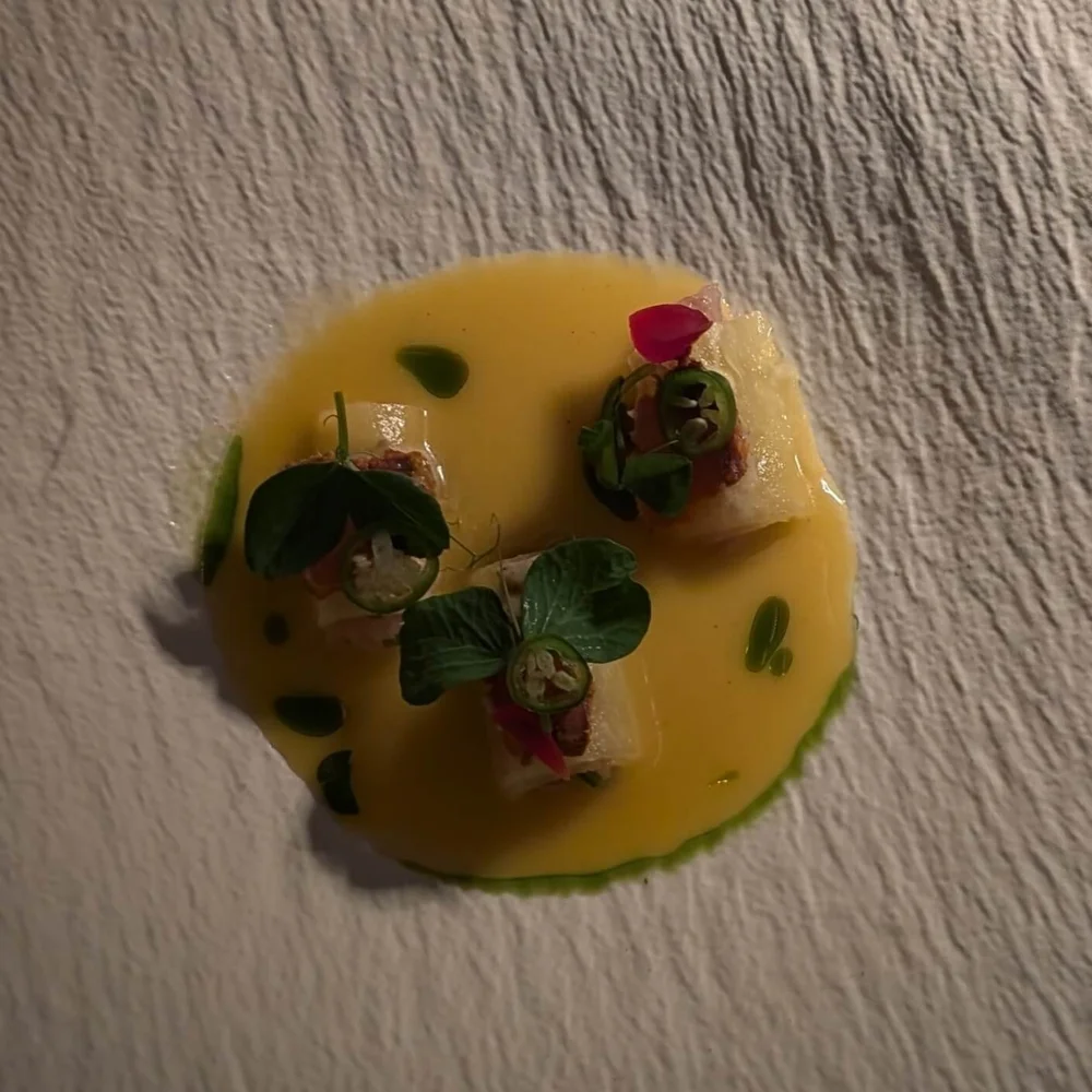 Al Pastor Sea Bass Tetela – Salt-cured sea bass sashimi with citrus emulsion and roasted pineapple purée — a refreshing Seaside appetizer.