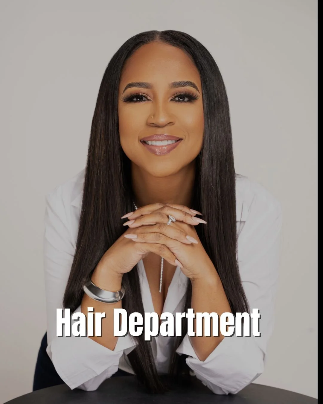 A woman with long dark hair smiling, wearing a white shirt, jewelry, and a ring, with the text "Hair Department" at the bottom of the image.