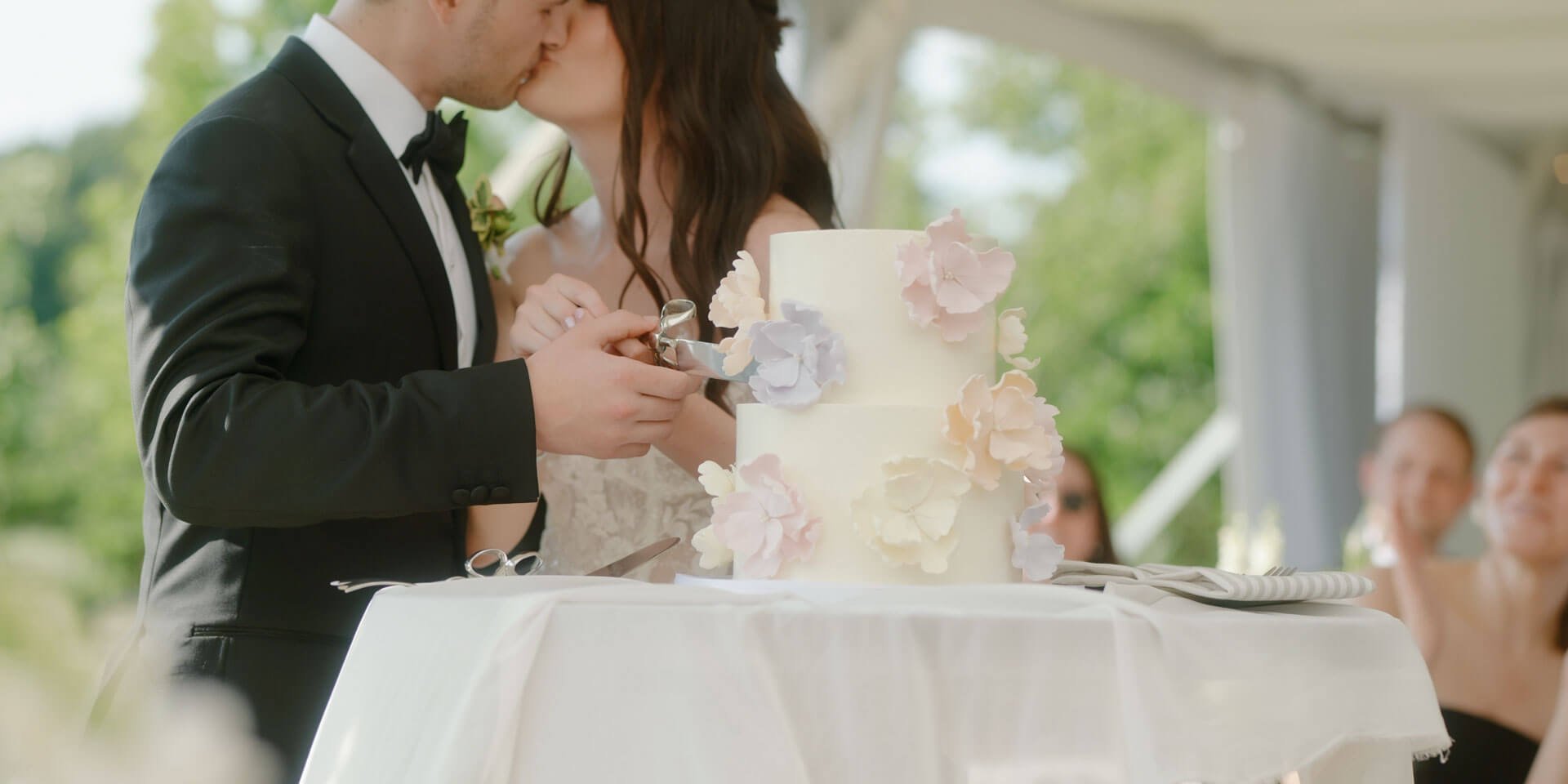 bride and groom kissing while cutting their wedding cake