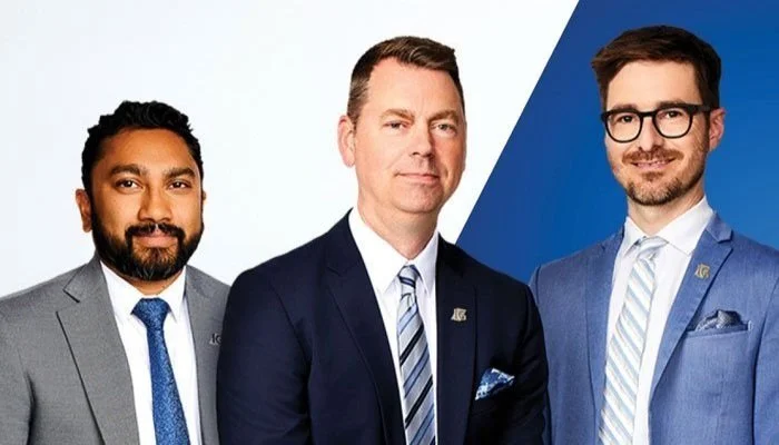 Three men in business suits standing together against a split background of white and blue.