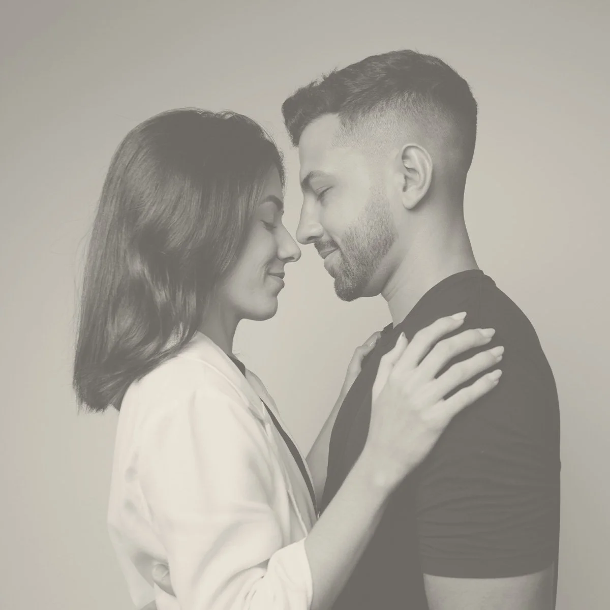 A black-and-white photo of a couple with foreheads touching, eyes closed, and hands on each other's shoulders.