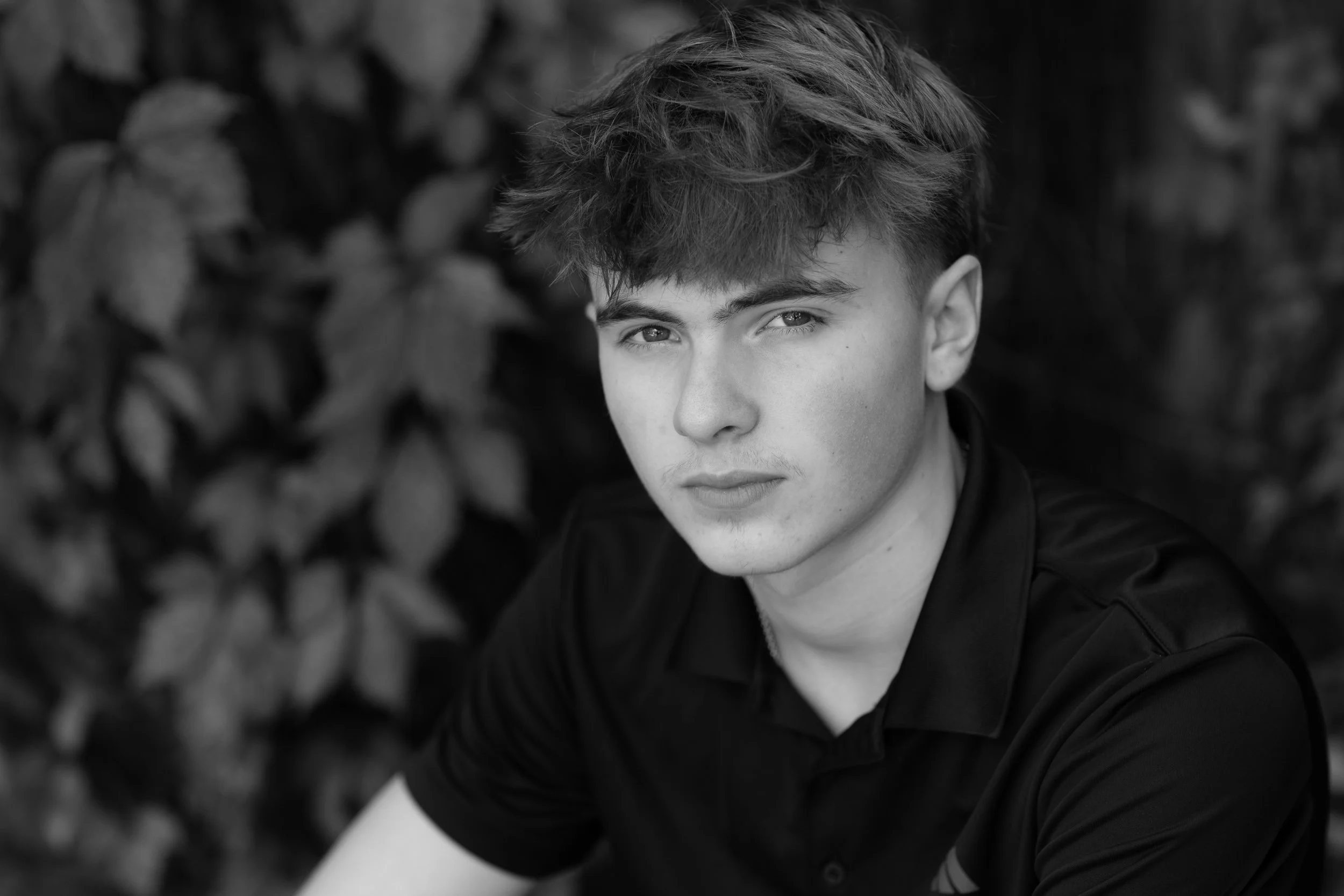 black & white portrait of senior boy with a muted background. 