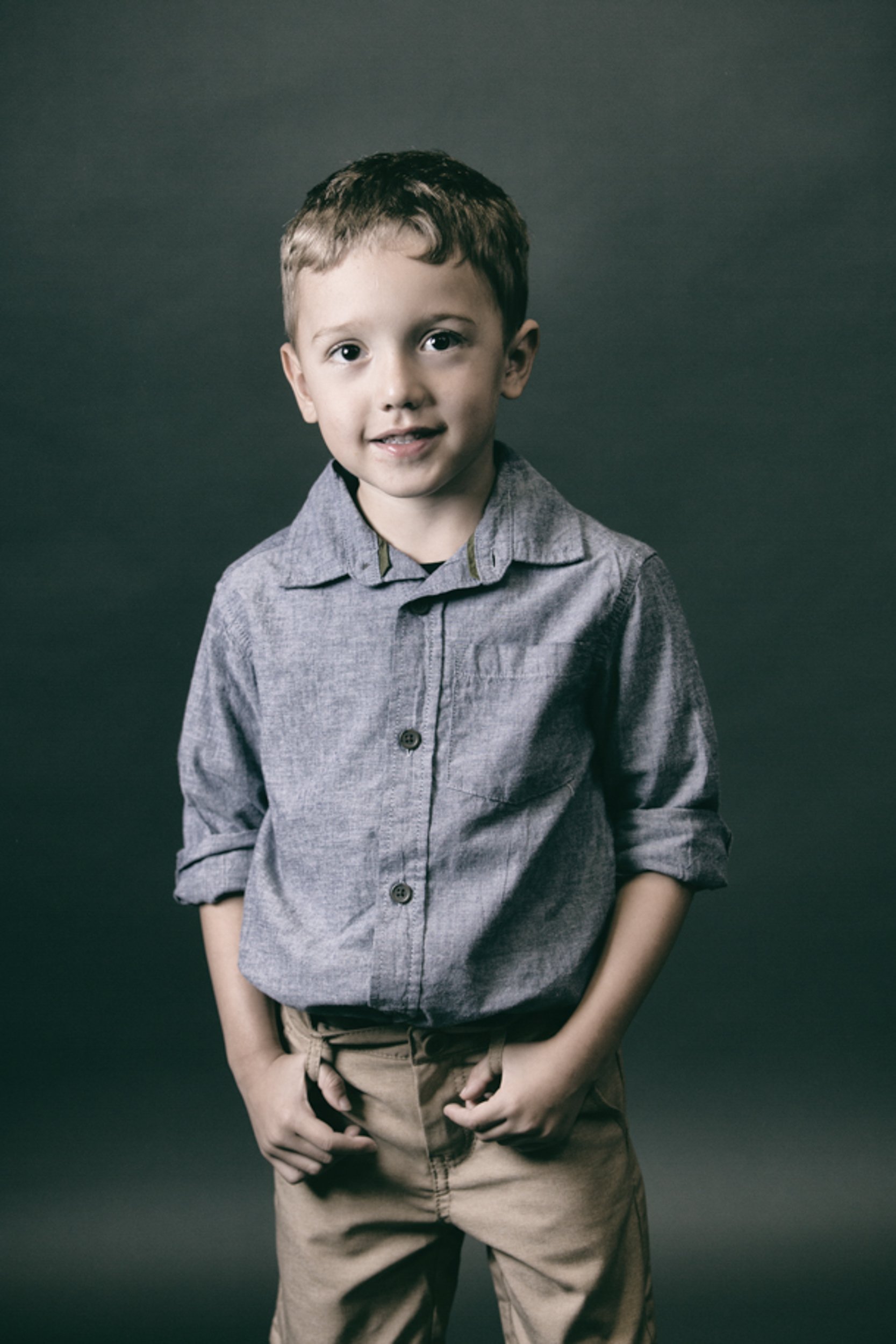 portrait of a boy hooking his belt loops smiling at the camera