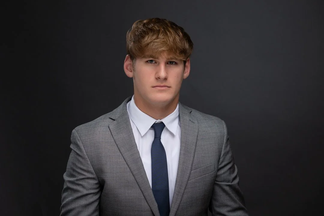 senior boy in a suit with a grey background