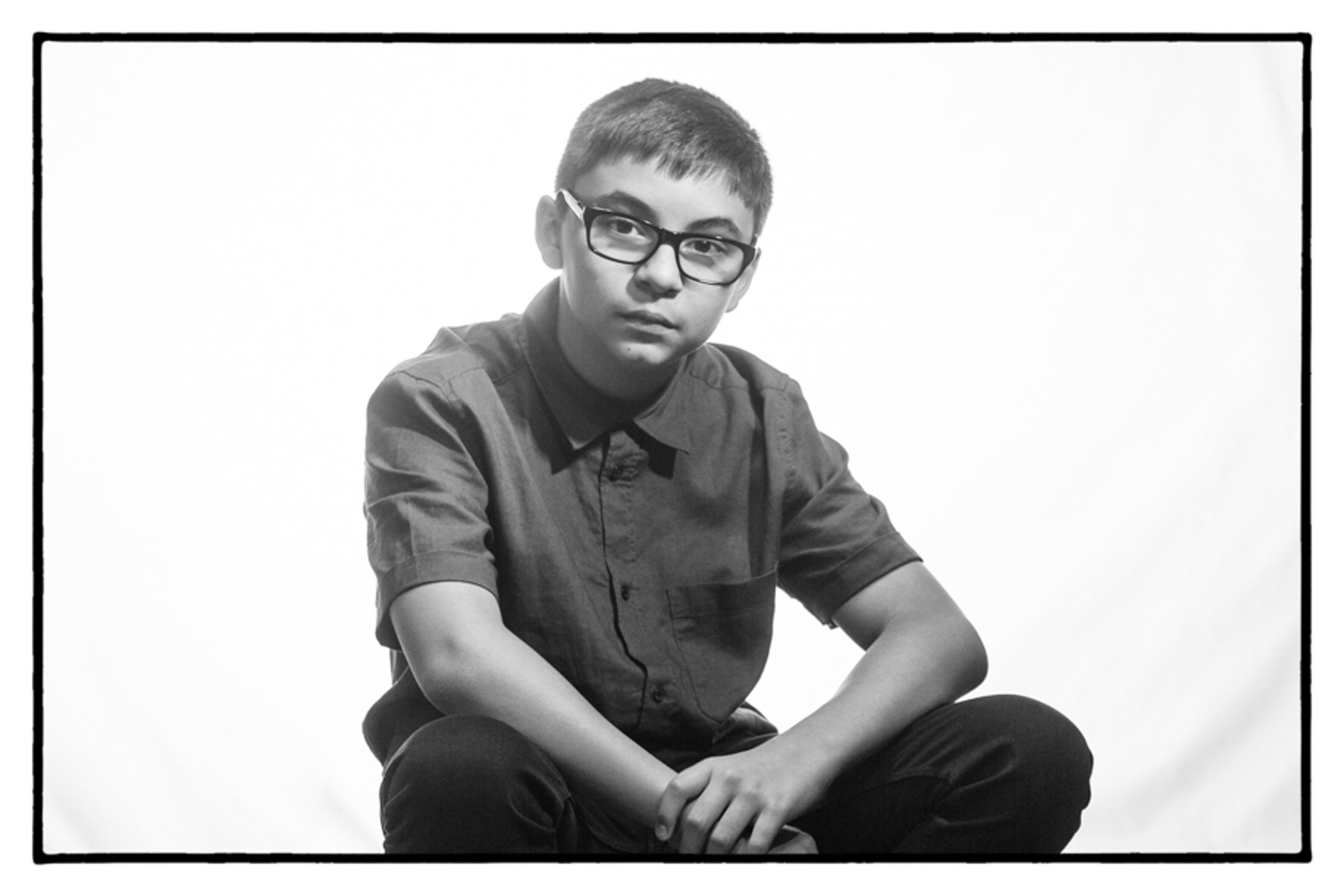 black and white portrait of boy leaning in on his knees looking at the camera