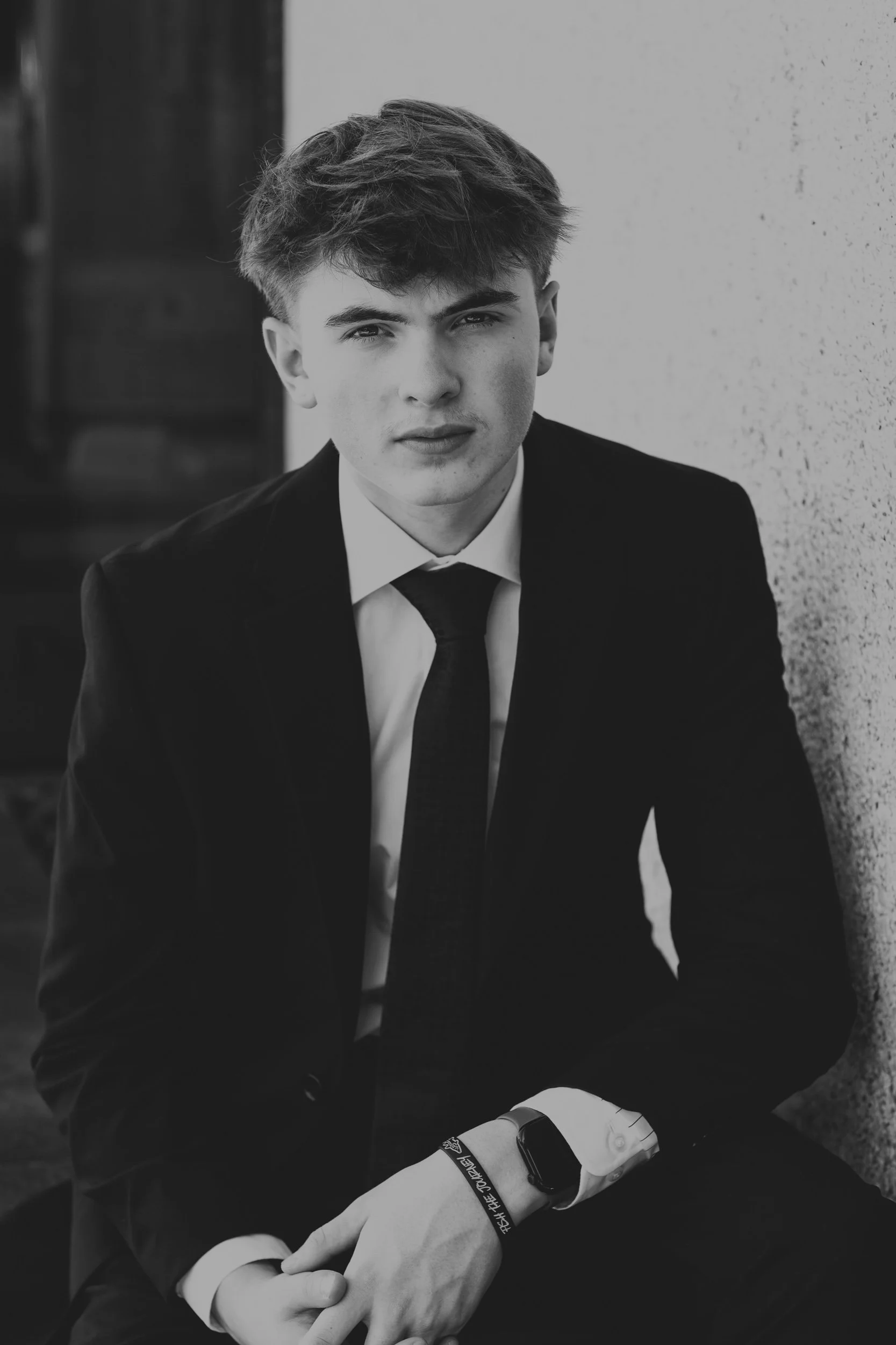 black & white portrait of senior boy in a suit outside.