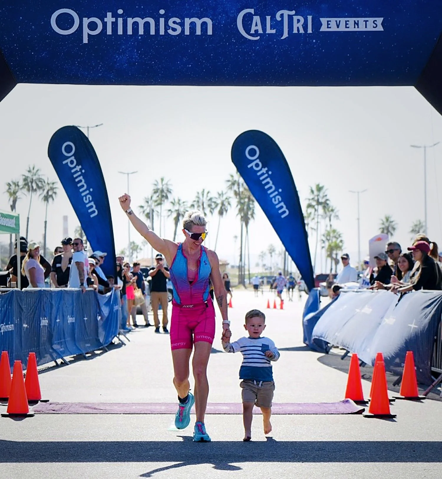 Rebekah crossing the Cal Tri finish line holding her son William's hand
