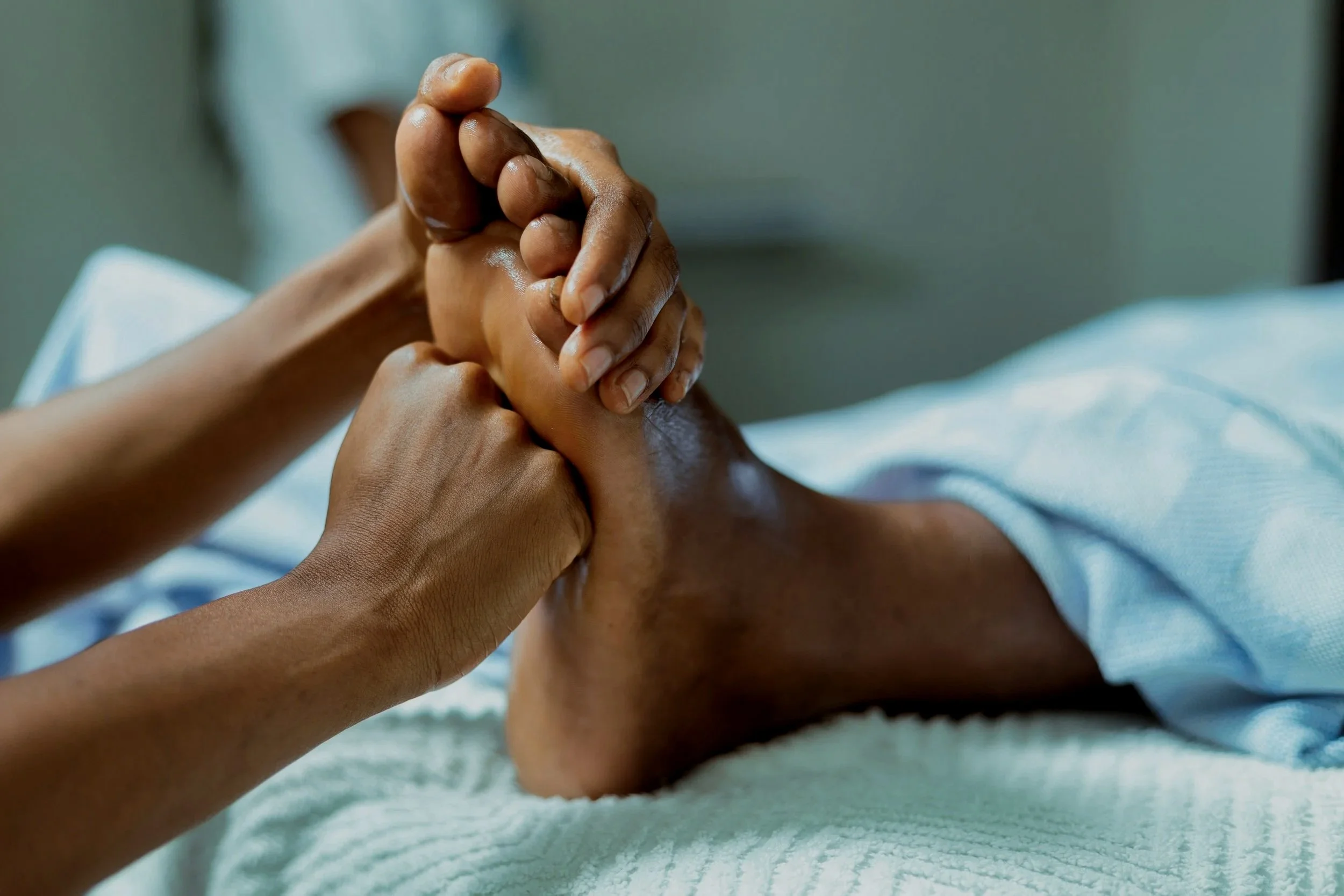 Close-up of a massage therapist giving a foot massage using reflexology on a massage table.