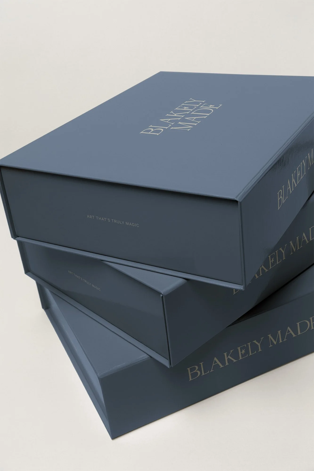 Three stacked blue boxes with gold lettering reading "BLAKELEY MADE" and the phrase "ART THAT'S TRULY MAGIC" on the sides.