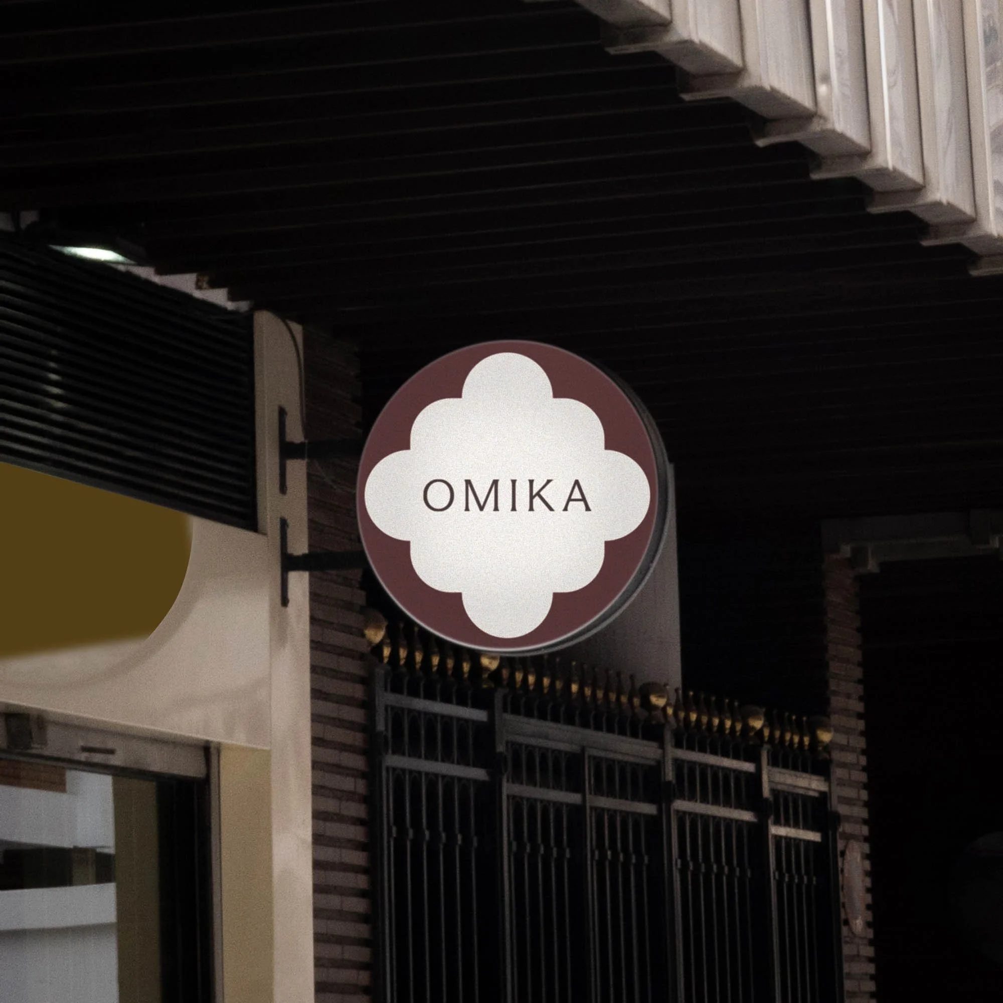 Storefront sign with the word 'OMIKA' on a decorative background.