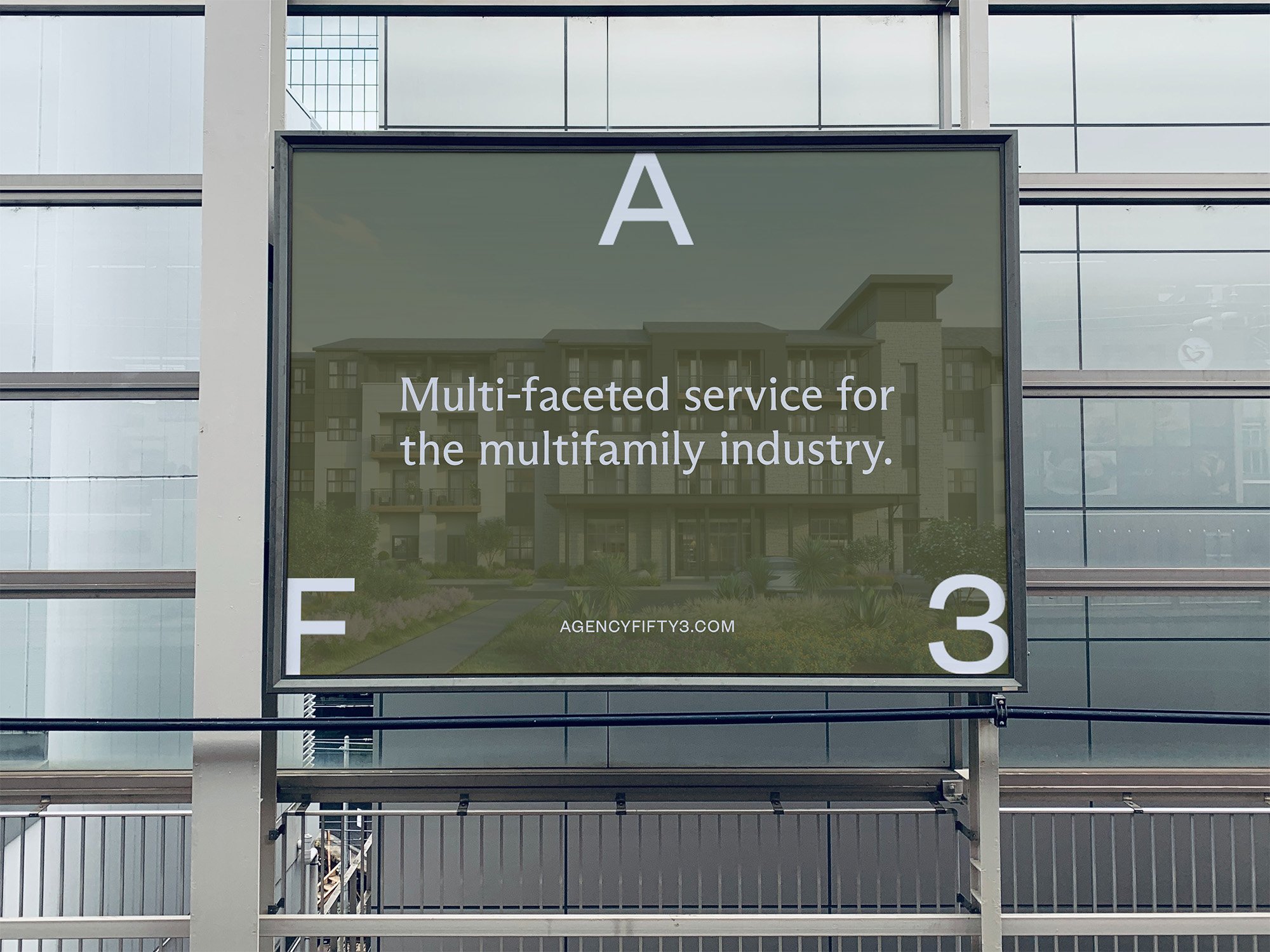 Billboard advertising multi-faceted services for the multifamily industry, situated on a building with glass windows.