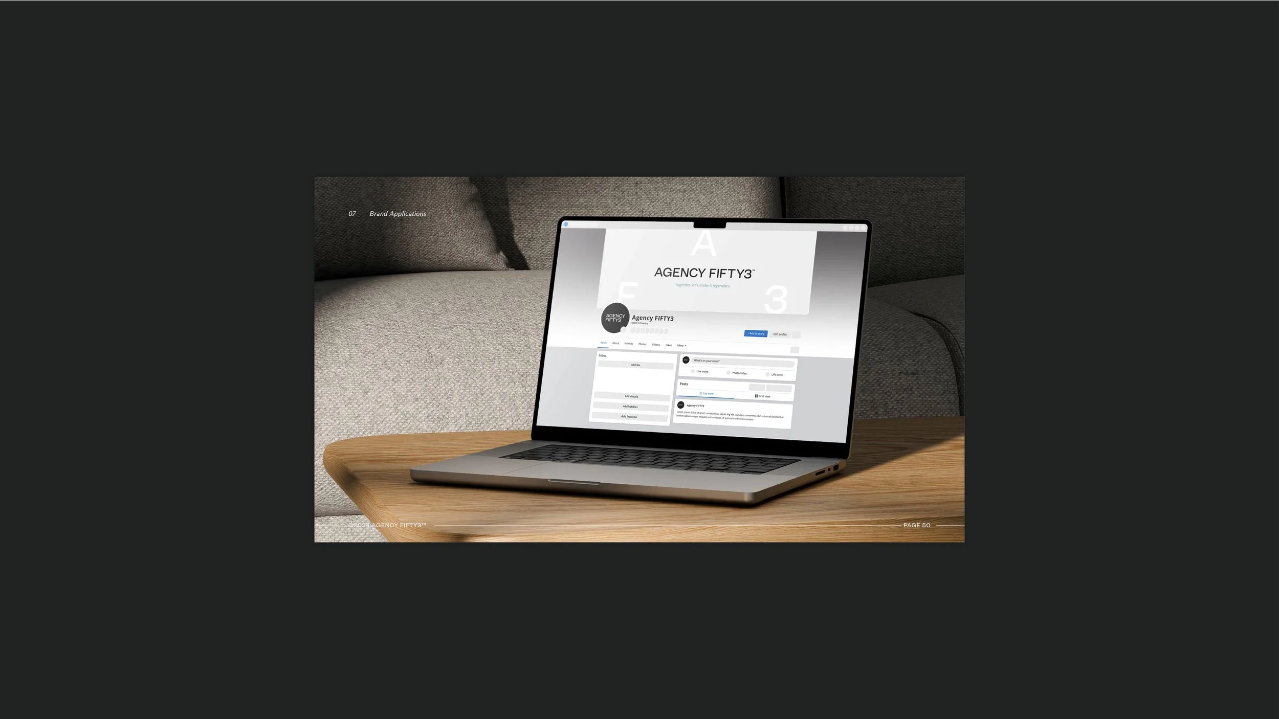 Laptop on a wooden table displaying a social media profile for Agency Fifty3, with a gray couch in the background.