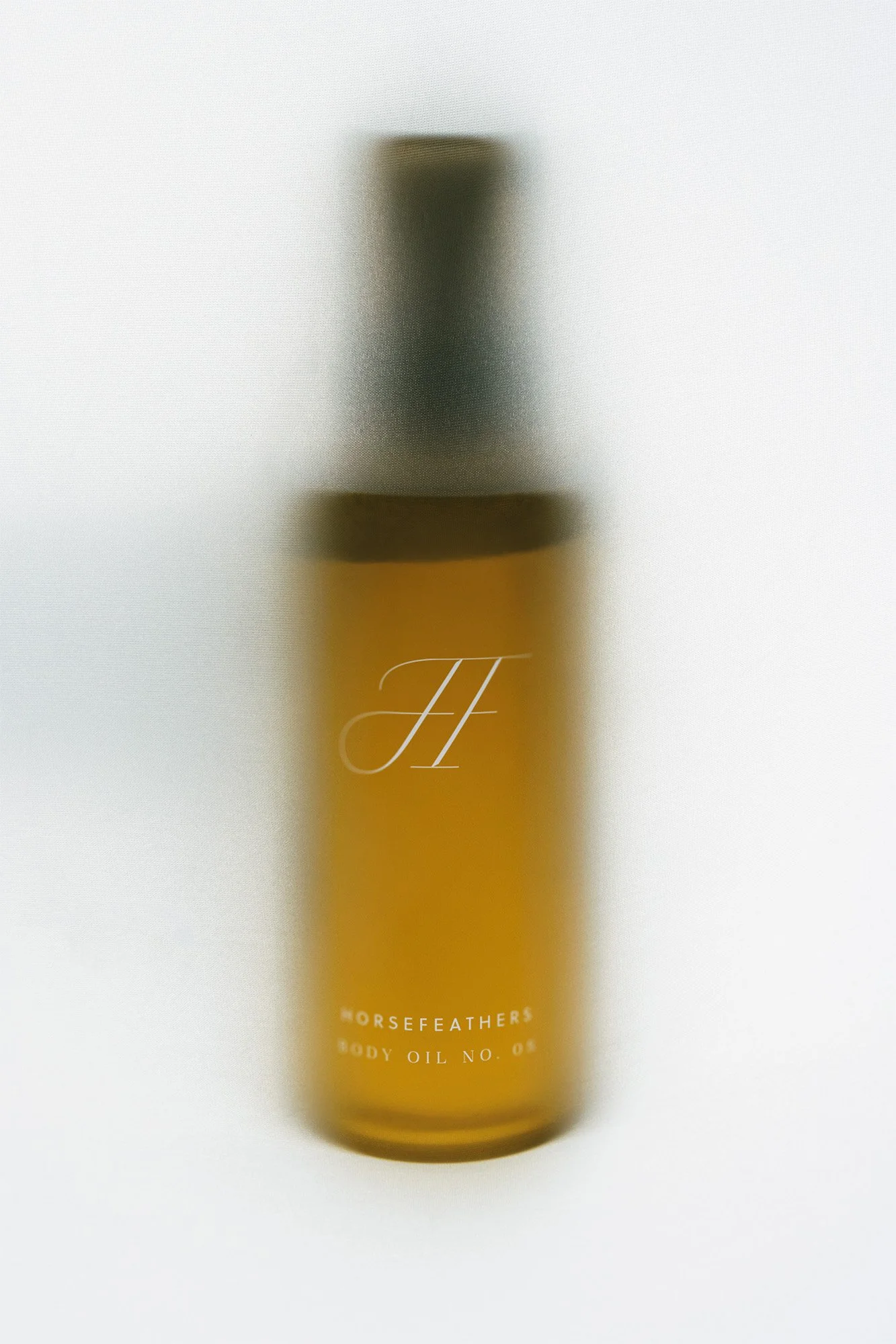 Blurry image of a yellow bottle labeled 'Horsefeathers Body Oil No. 05'.
