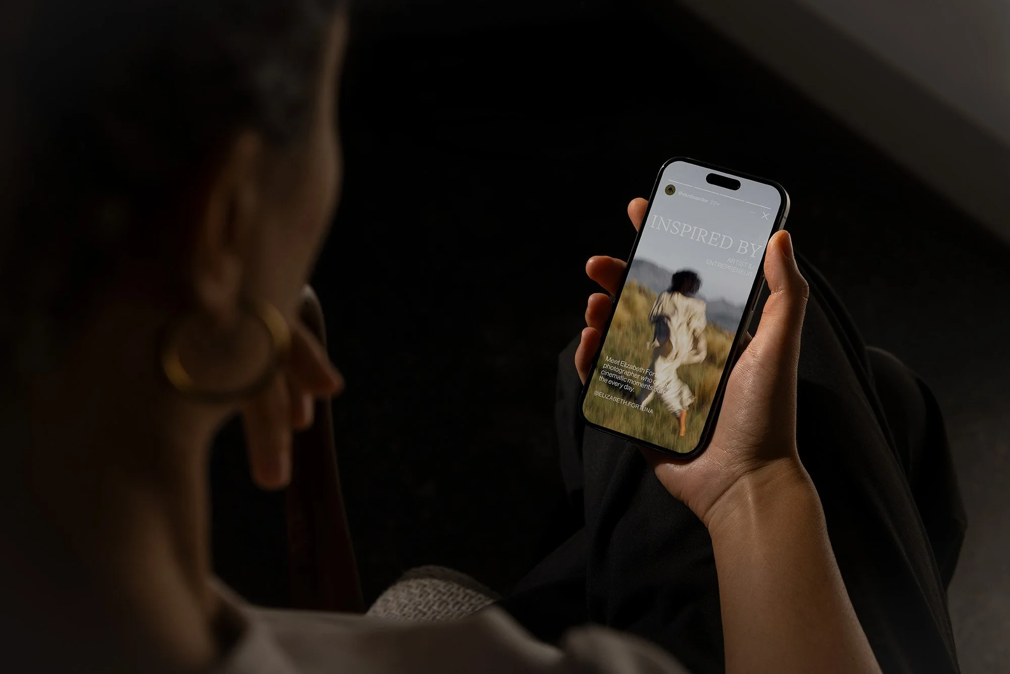 Person holding a smartphone, showing a magazine cover titled 'Inspired By', with a woman walking in a field.