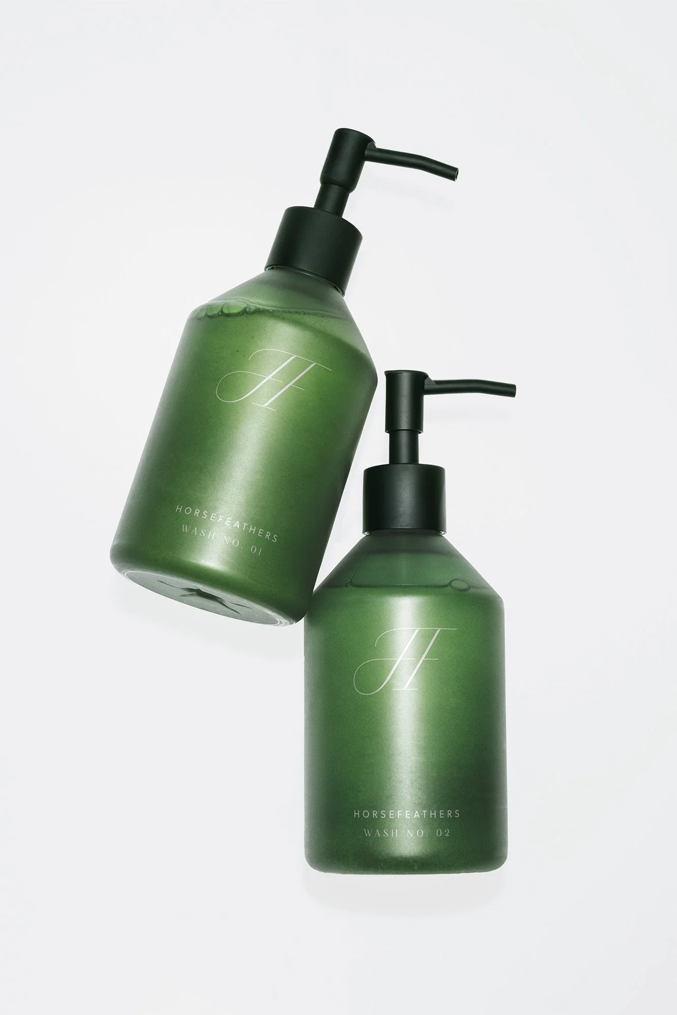 Two green bottles of Horsefeathers Wash soap with black pump dispensers on a white background.