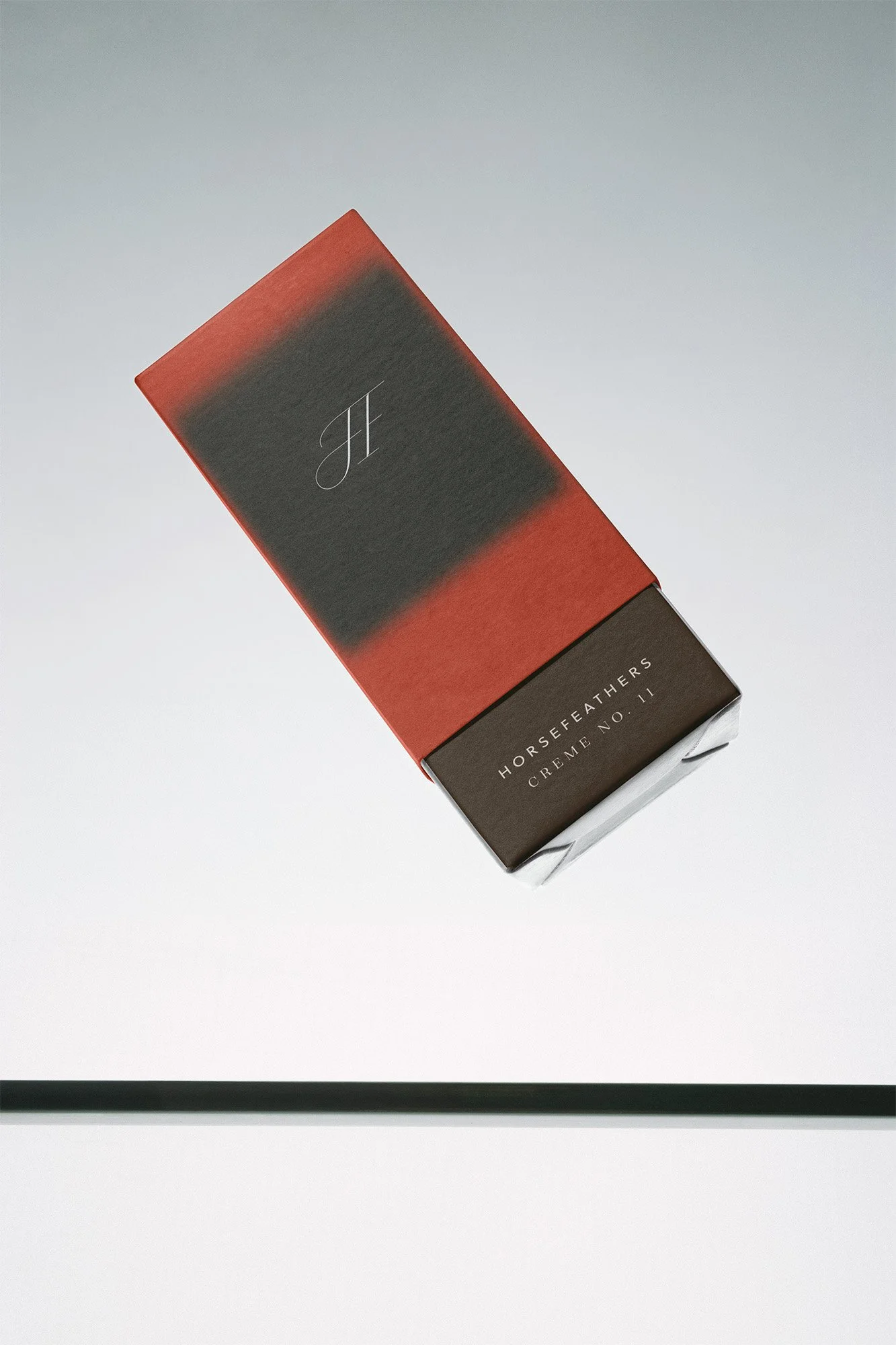 A box of Horsefeathers Crème No. 11 with a gradient design on the packaging, floating above a reflective surface.