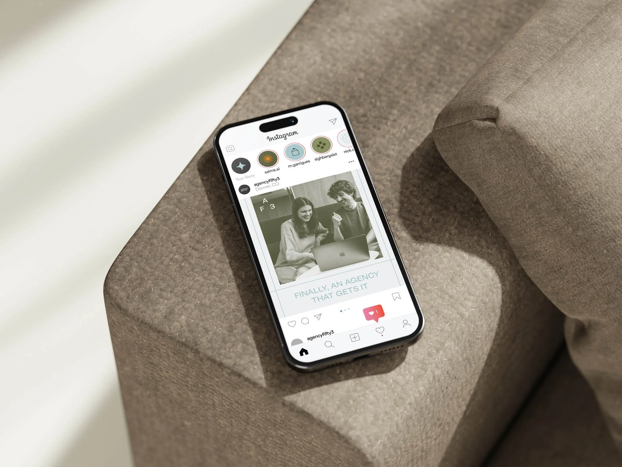 Smartphone displaying an Instagram post with two people working on a laptop.